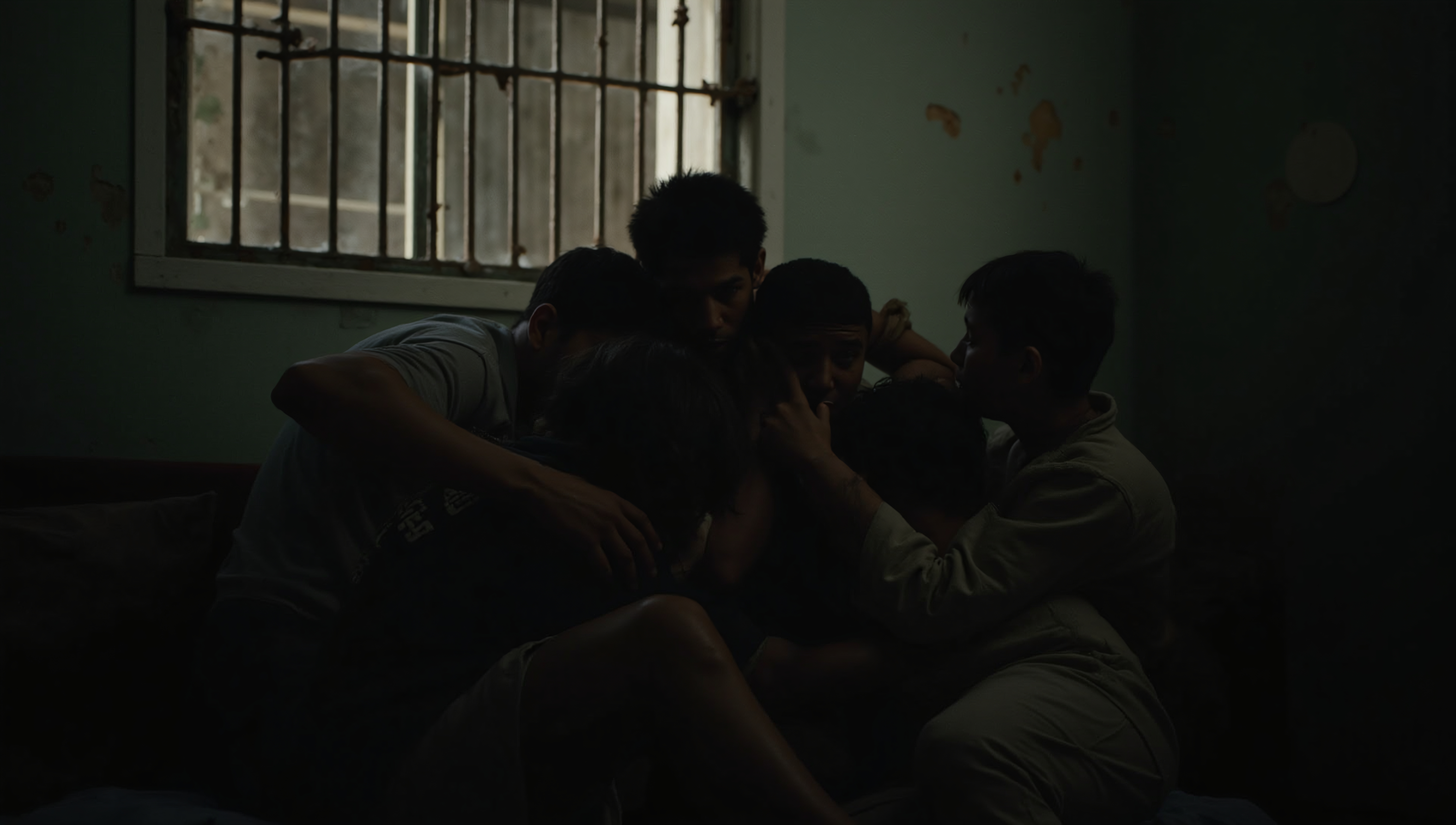 Group Huddle in Dimly Lit Room with Barred Window