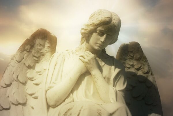 Serene angel statue against radiant time-lapse sky.