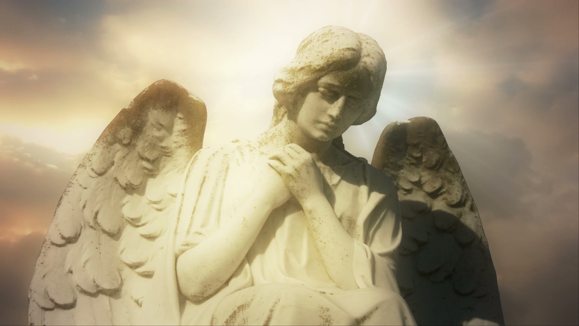 Serene angel statue against radiant time-lapse sky.