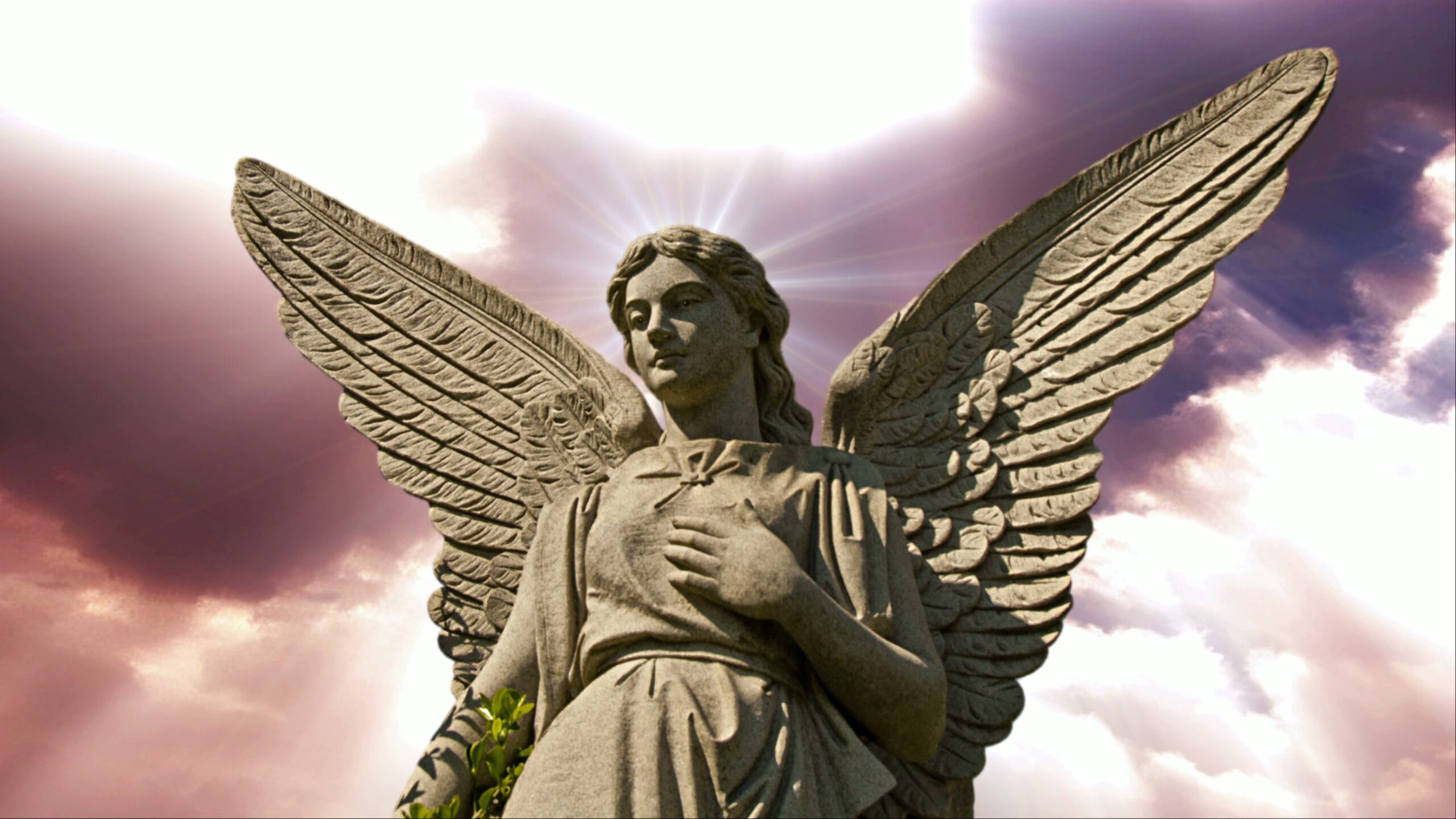 4K video loop of a stone angel statue with radiant wings and a halo effect against a dramatic purple and white time-lapse sky.