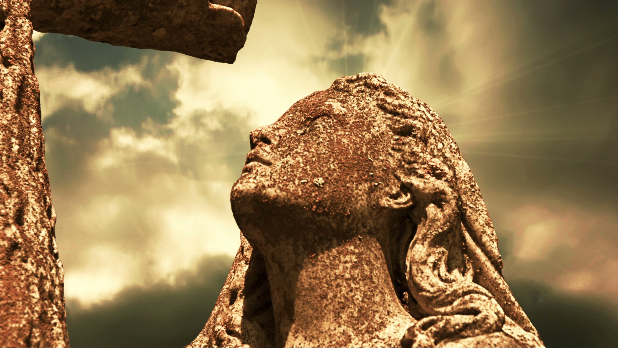 4K video loop of a weathered stone statue looking skyward with dramatic time-lapse clouds and sun rays.