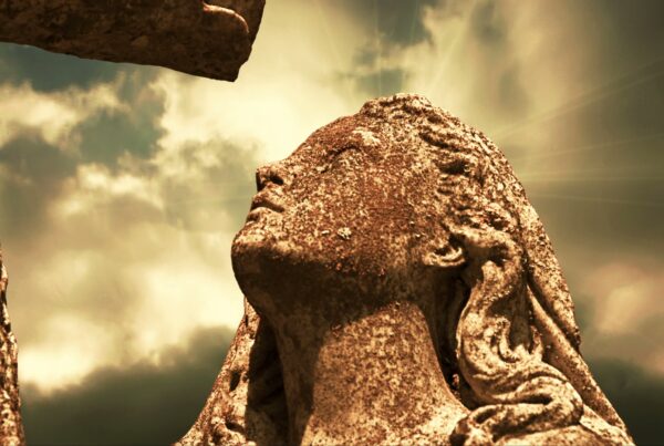 Stone statue under dramatic time-lapse sky gazes up towards the divine, bathed in sunlight, evoking spirituality and contemplation.
