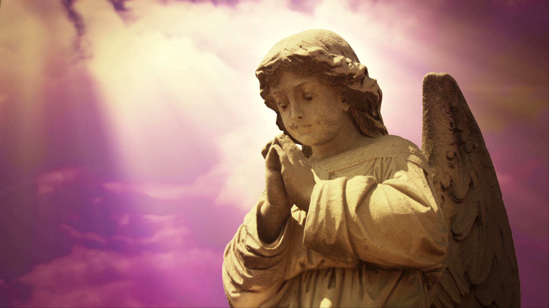 A serene stone statue of an angel on time-lapse clouds, video animation loop.