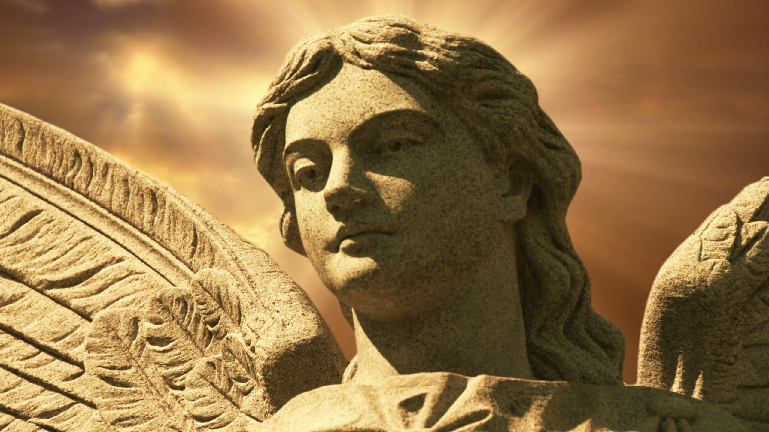 4K looping video of a stone angel statue with radiant halo effects in a golden time-lapse sky.