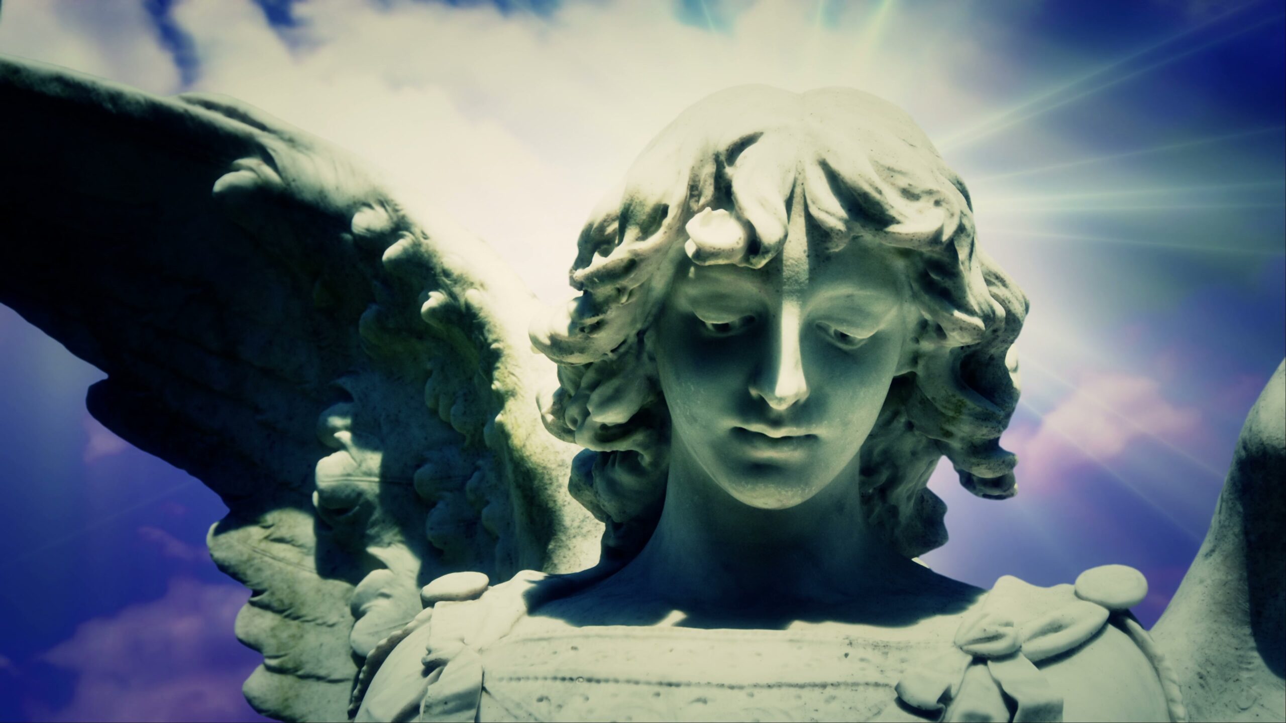 4K video loop of an Angel statue with open wings against a heavenly time-lapse sky, illuminated by ethereal light.