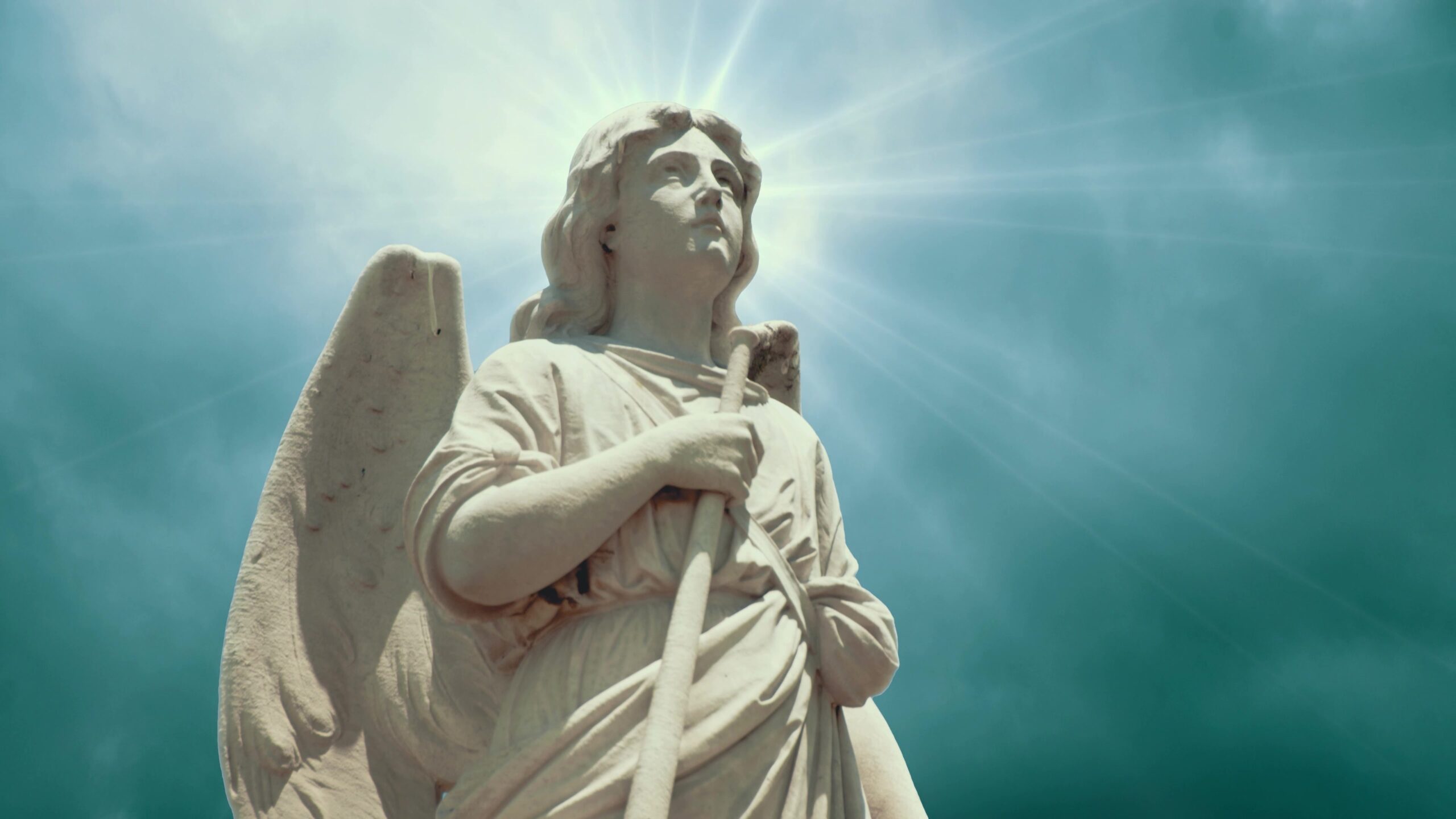 4K video loop of a stone angel statue with radiant sky background, sunlight creating a halo effect, surrounded by time-lapse clouds.