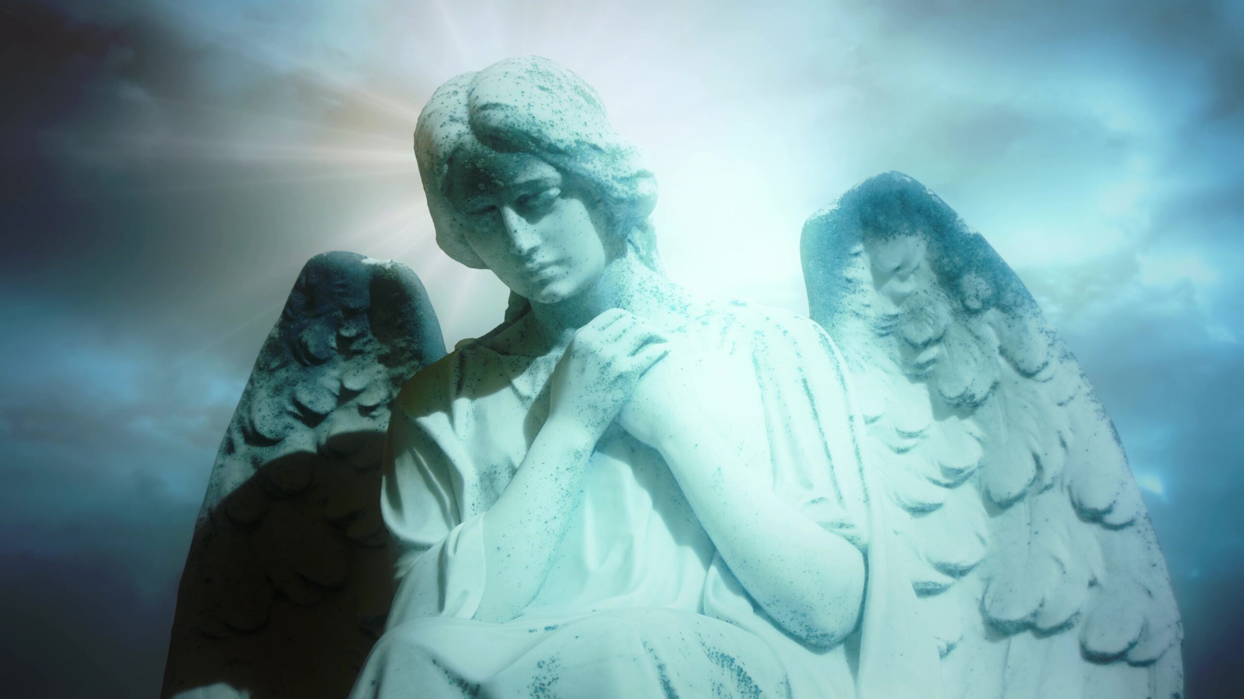 Marble angel statue with serene expression illuminated by radiant light against a backdrop of blue time-lapse clouds and bright sky.