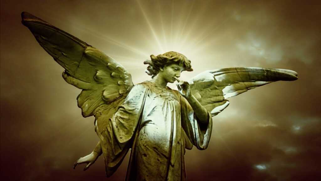 Stone angel statue with widespread wings set against a radiant, time-lapse cloudy sky, highlighting its serene expression and symbol of contemplation under diffused sunlight.