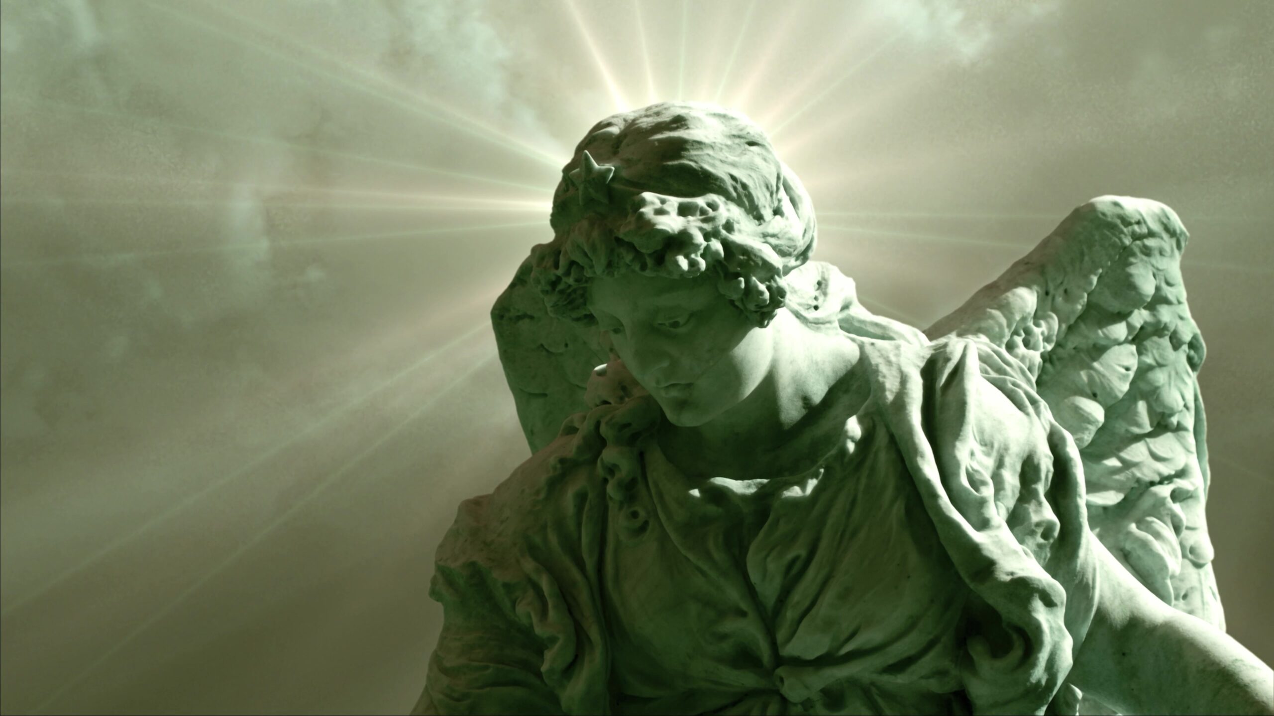 Statue of an angel glowing with light in heavenly time-lapse skies.