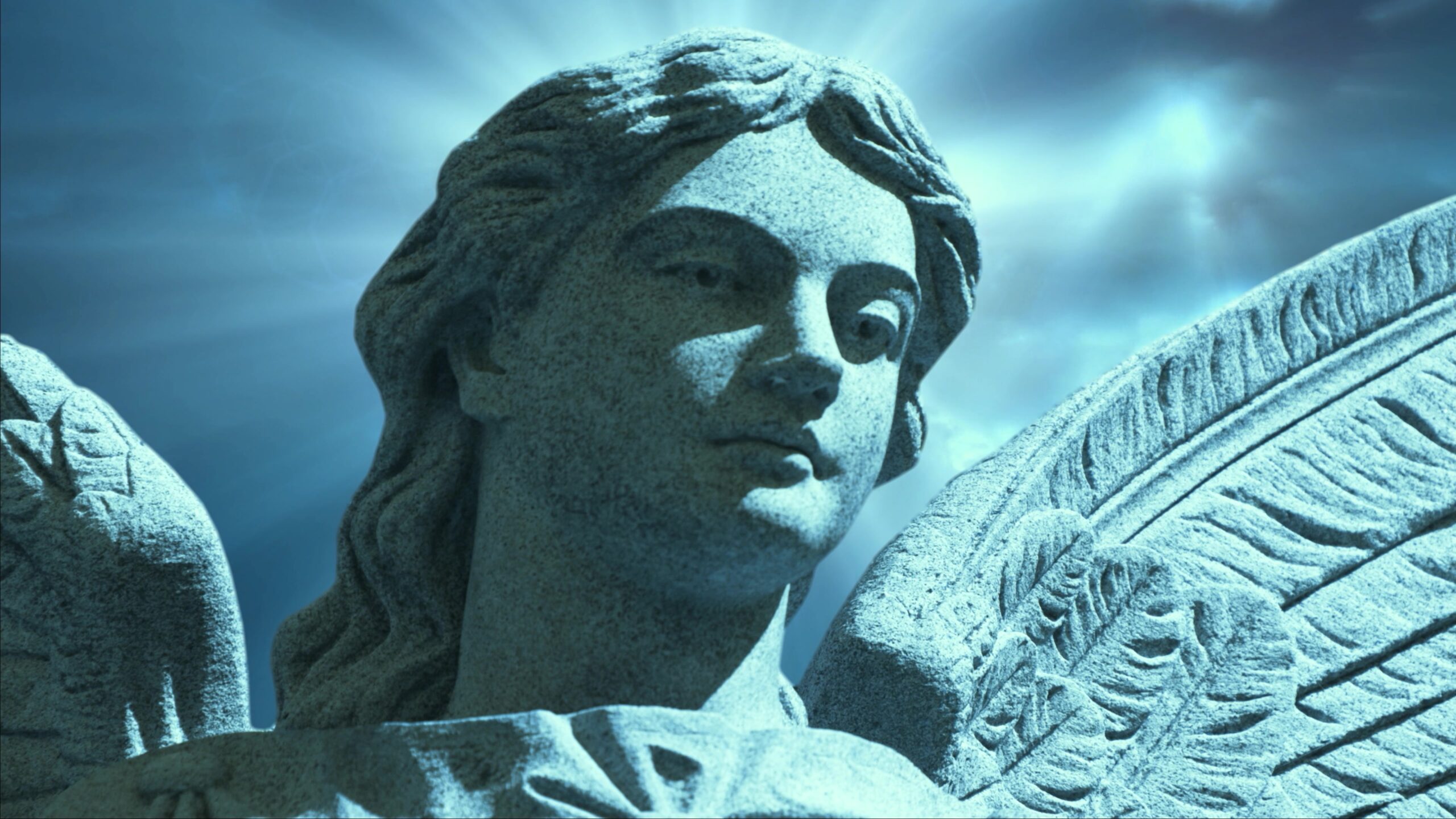 4K video loop of a stone angel statue with wings, set against a radiant blue time-lapse sky, conveying serenity and spirituality.