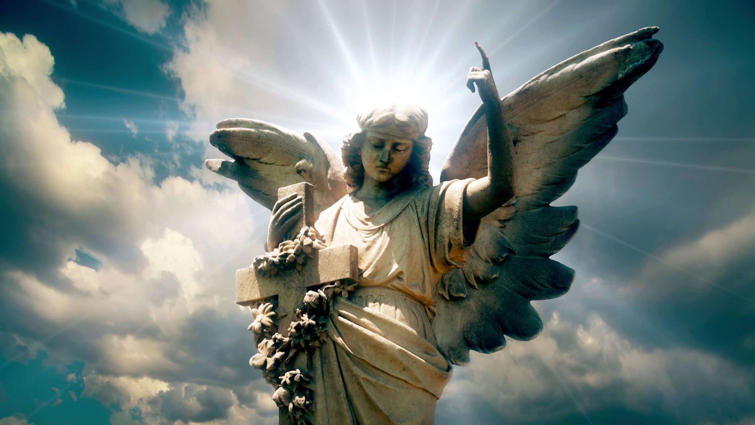 4K looping video of a stone angel statue standing against a time-lapse cloudy sky with sunlight creating a halo effect.