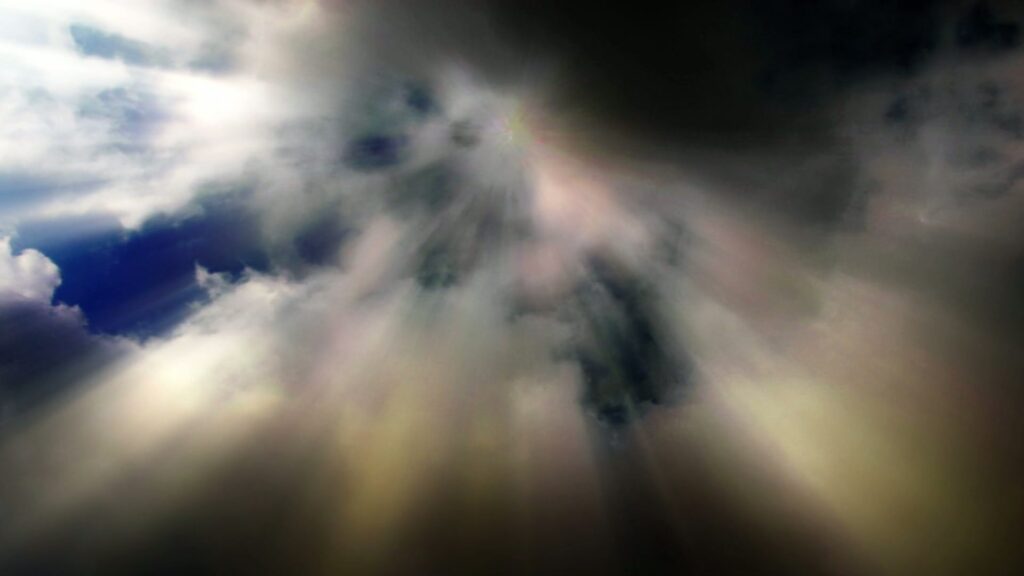 This looping video captures a dramatic sky predominantly filled with dark time-lapse clouds. Rays of light penetrate through the clouds, creating a striking effect.