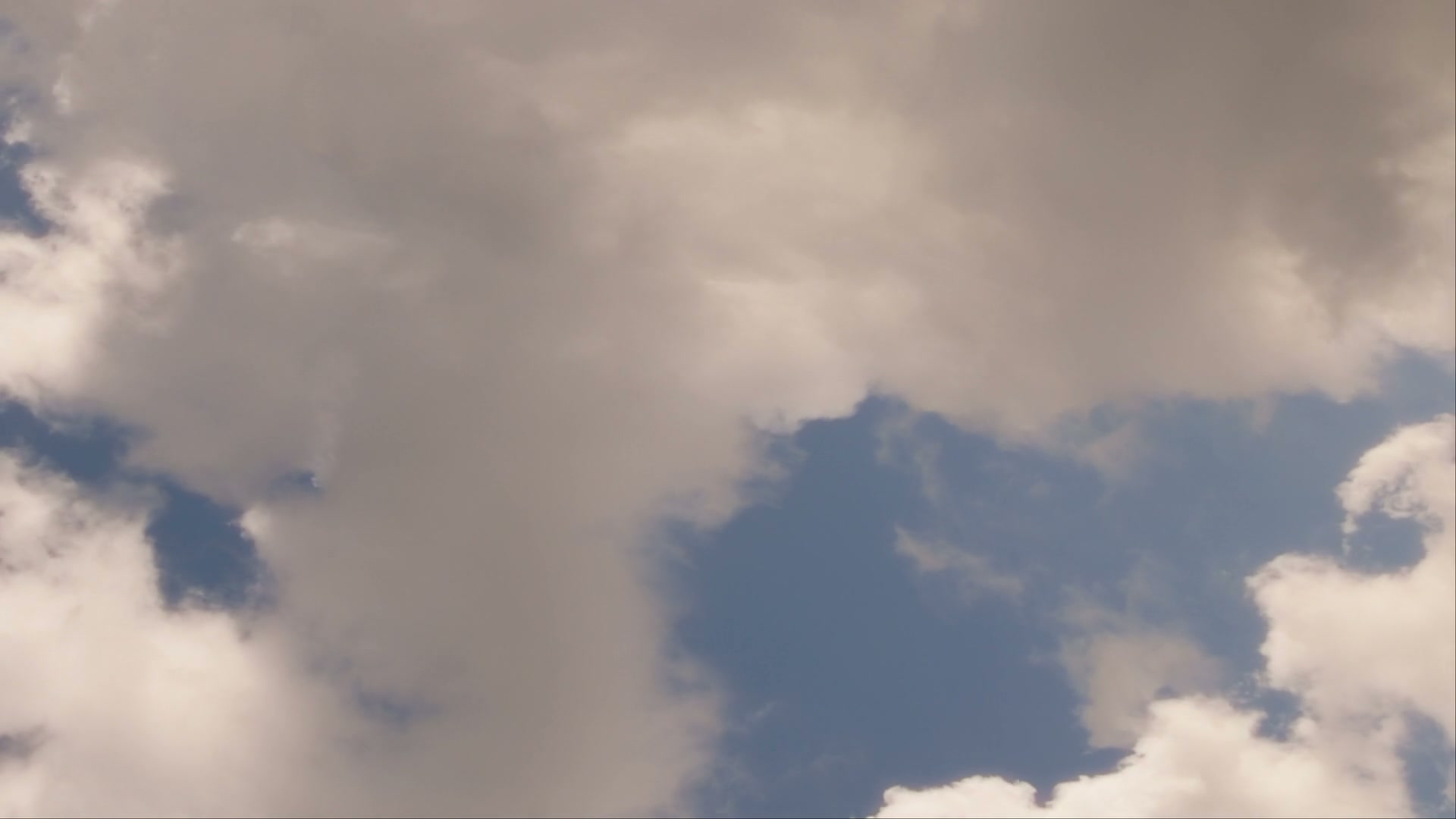 Fluffy white and gray time-lapse clouds against a blue sky, capturing a serene and tranquil atmosphere.