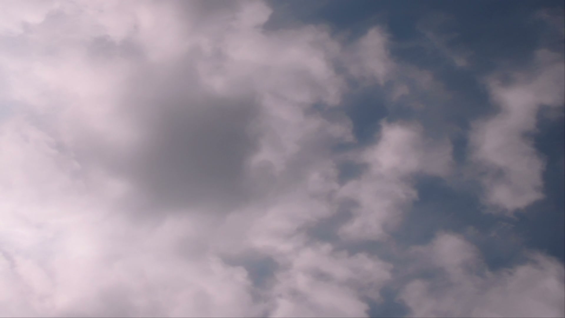 A tranquil view of a clear blue sky with scattered fluffy time-lapse clouds, showcasing a serene and peaceful atmosphere.