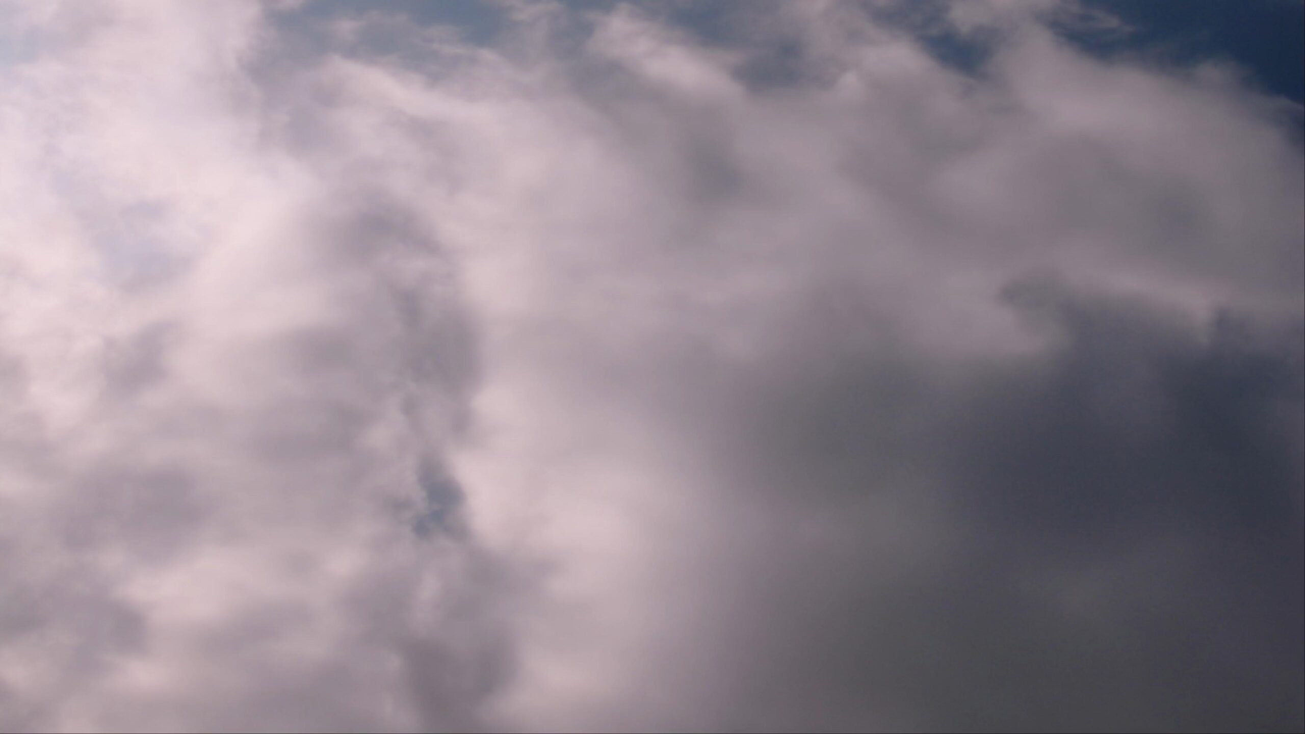 Fluffy white tim-lapse clouds in a blue sky on a sunny day.