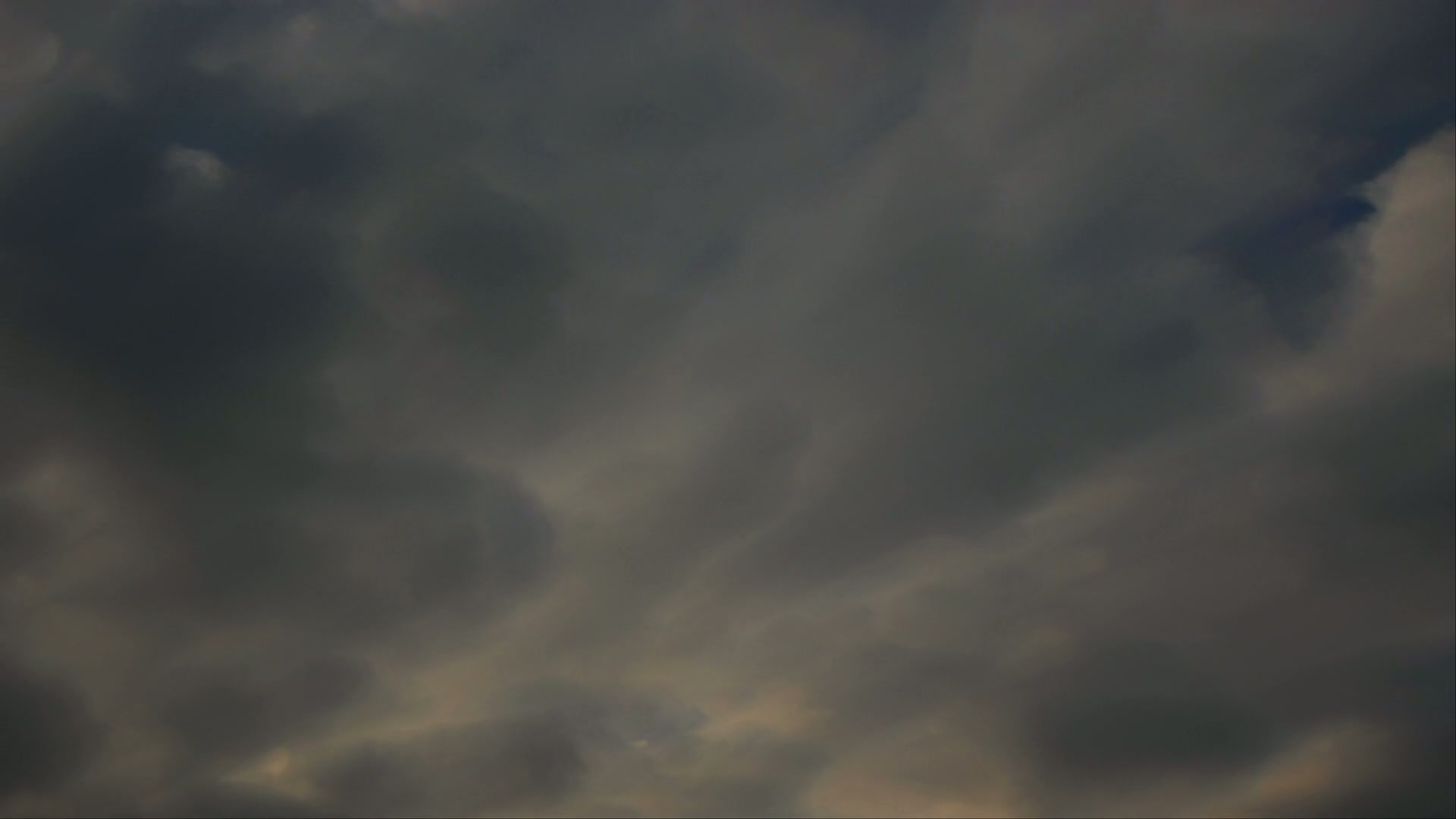 Dark and dramatic overcast sky with dense, layered time-lapse clouds creating an ominous and moody atmosphere, suggesting an approaching storm or evening weather change.