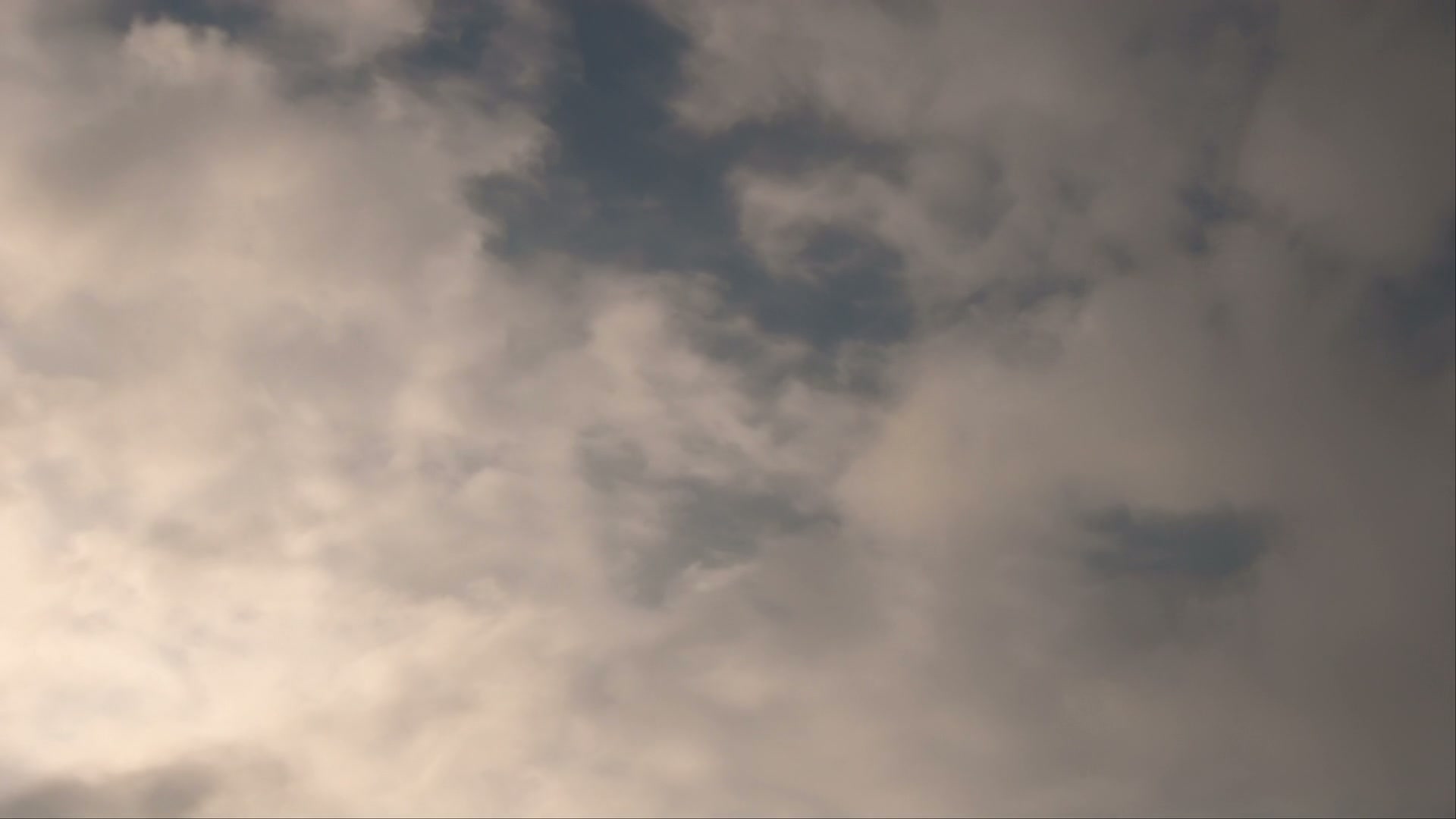 Soft, time-lapse clouds drifting across a blue sky, showcasing a tranquil and serene atmosphere in a natural landscape.
