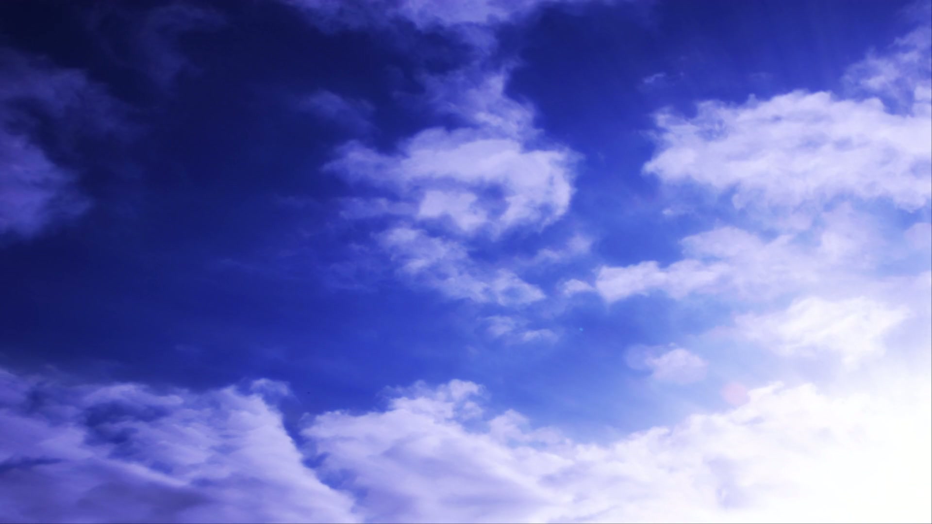 A tranquil video of a blue sky with wispy time-lapse clouds and sunlight casting a serene atmosphere.