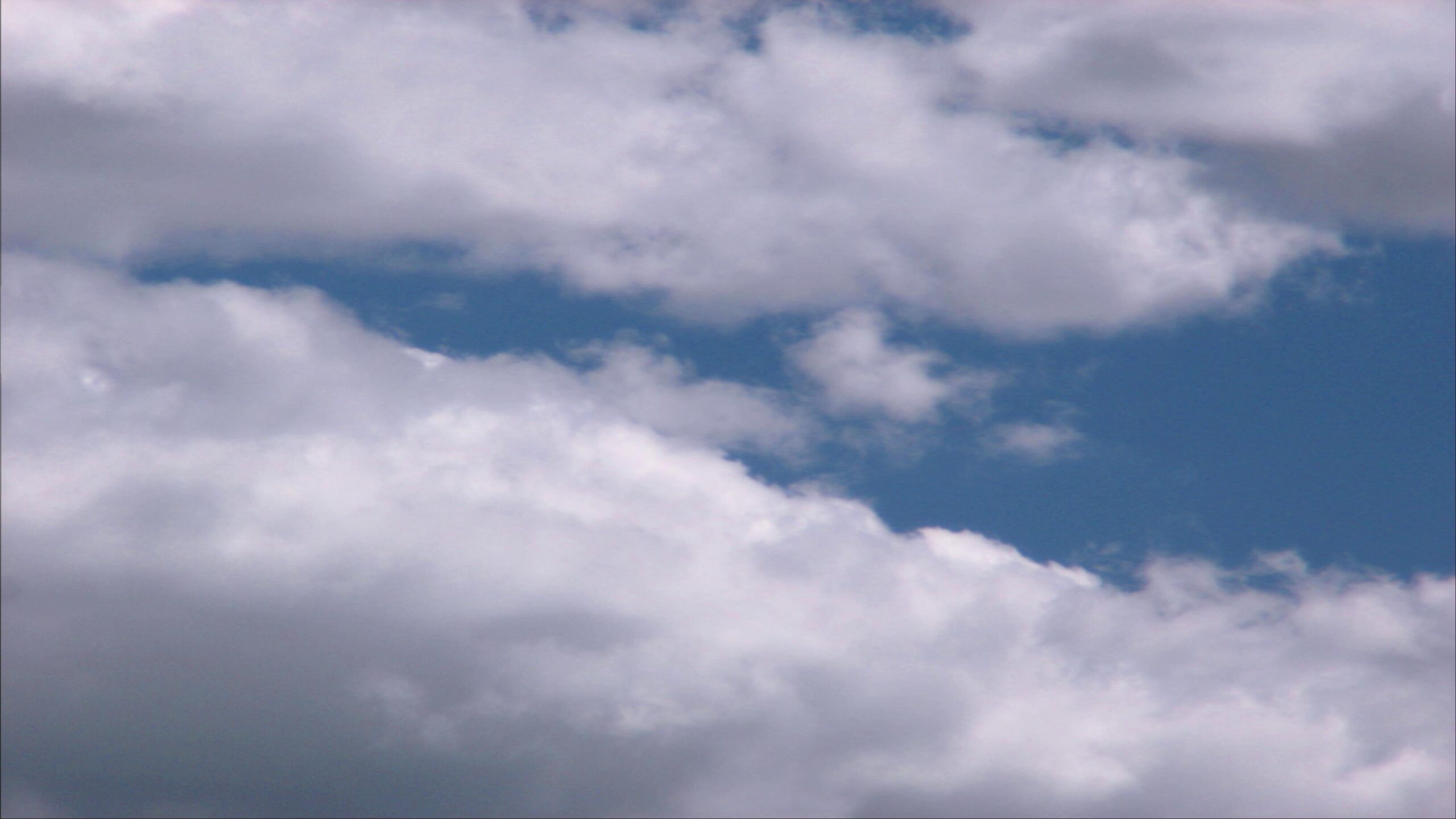 4K video of fluffy white time-lapse clouds against a serene blue sky, creating a peaceful and tranquil outdoor scene.