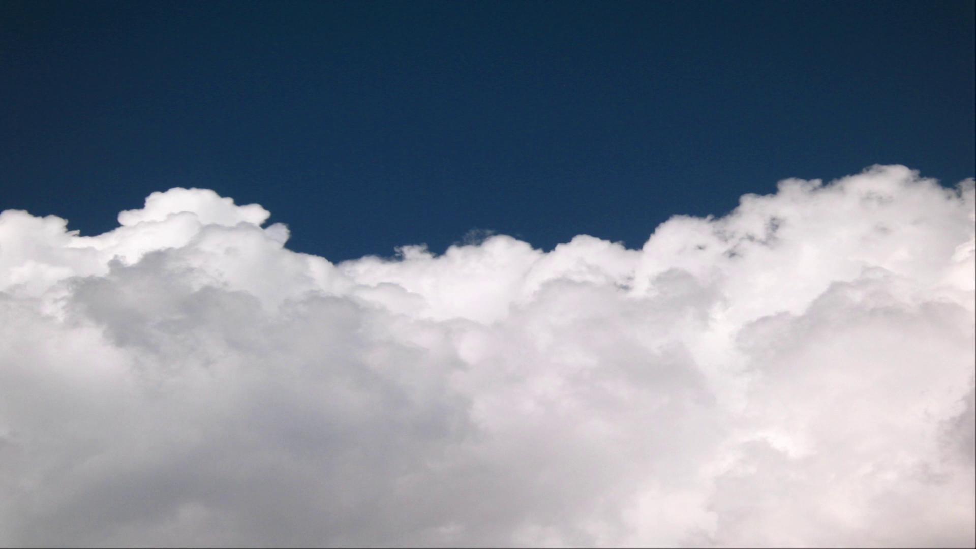 HD video timelapse of drifting white clouds over dark blue sky