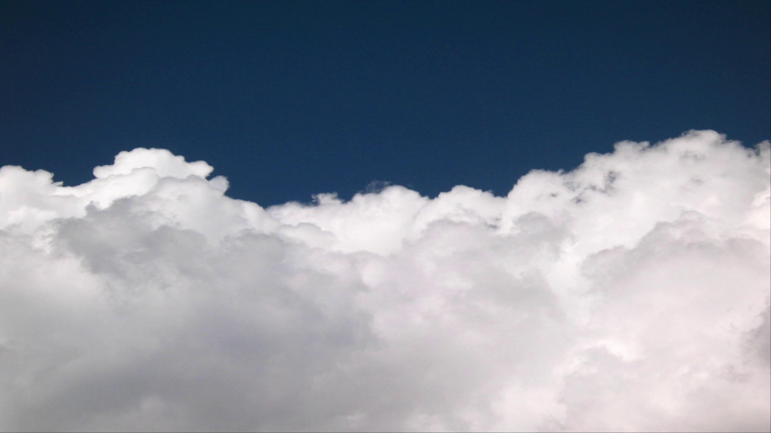 4K video of fluffy white cumulus time-lapse clouds against a deep blue sky.