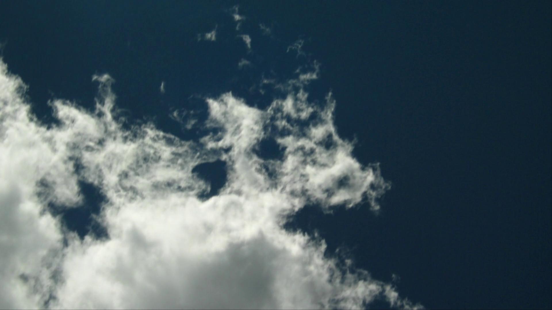 HD video of white fluffy time-lapse clouds in a deep blue sky.