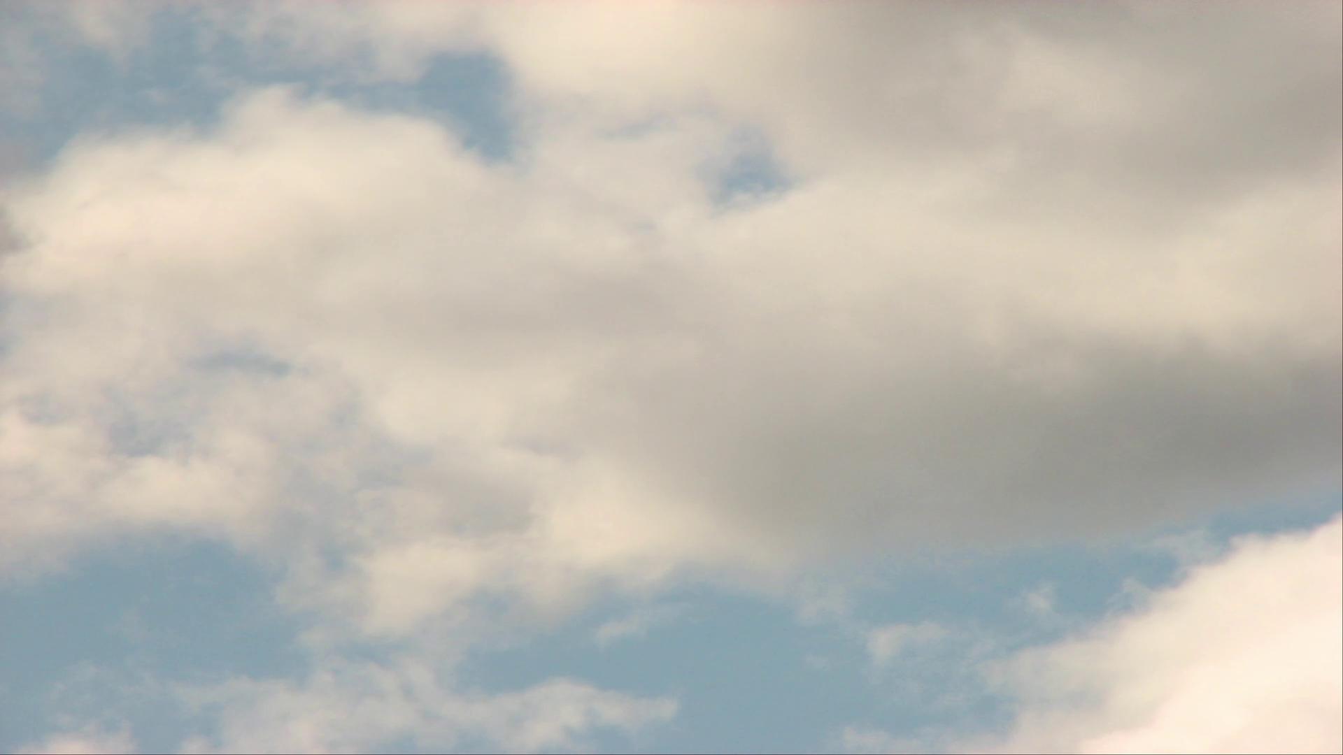 Fluffy white time-lapse clouds against a serene blue sky, creating a peaceful and calming atmosphere on a sunny day.