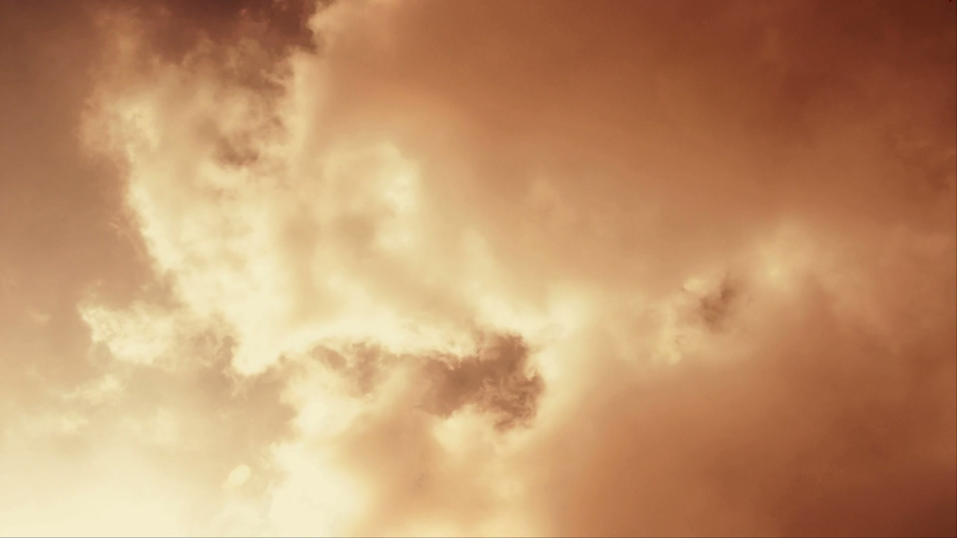A captivating HD video of a sky filled with warm-toned time-lapse clouds during sunset, highlighting the interplay of light and shadow, creating a tranquil and atmospheric scene.