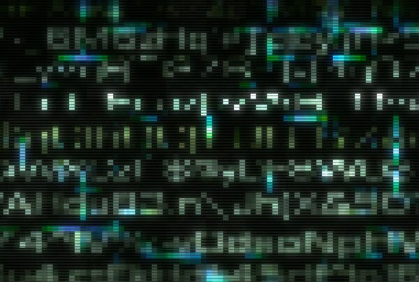 A digital screen displays glitchy video loop of pixelated text in white, blue, and green on a black background, resembling a vintage CRT monitor with a cyberpunk aesthetic.