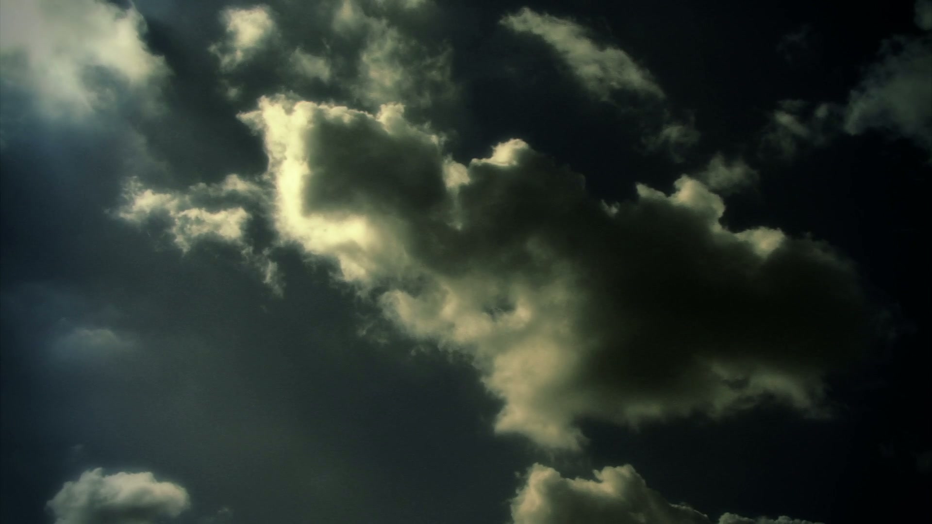 The video displays a dramatic sky filled with dark, billowing time-lapse clouds against a dimly lit background.