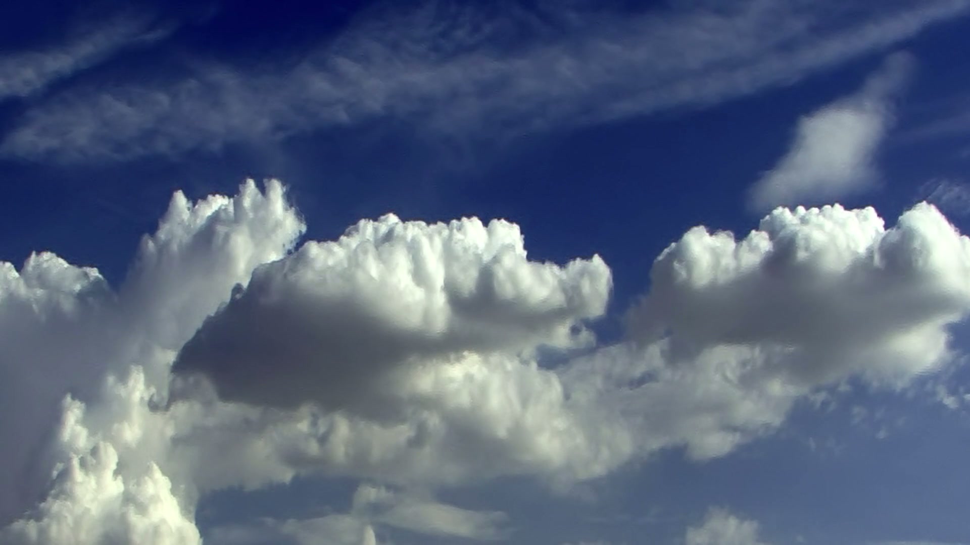 A blue sky with turbulent time-lapse white clouds.