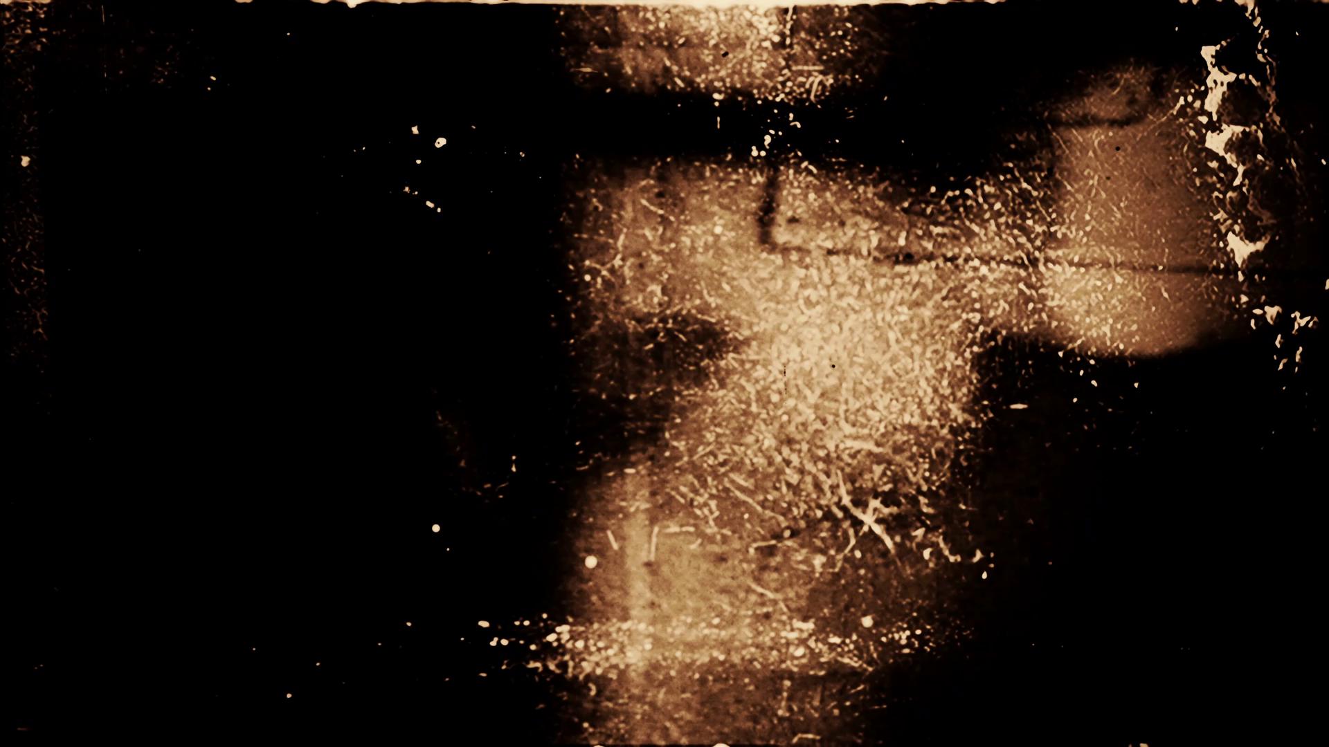 HD video loop of damaged 16mm film with scratches, specks, and warmth-toned shadows.