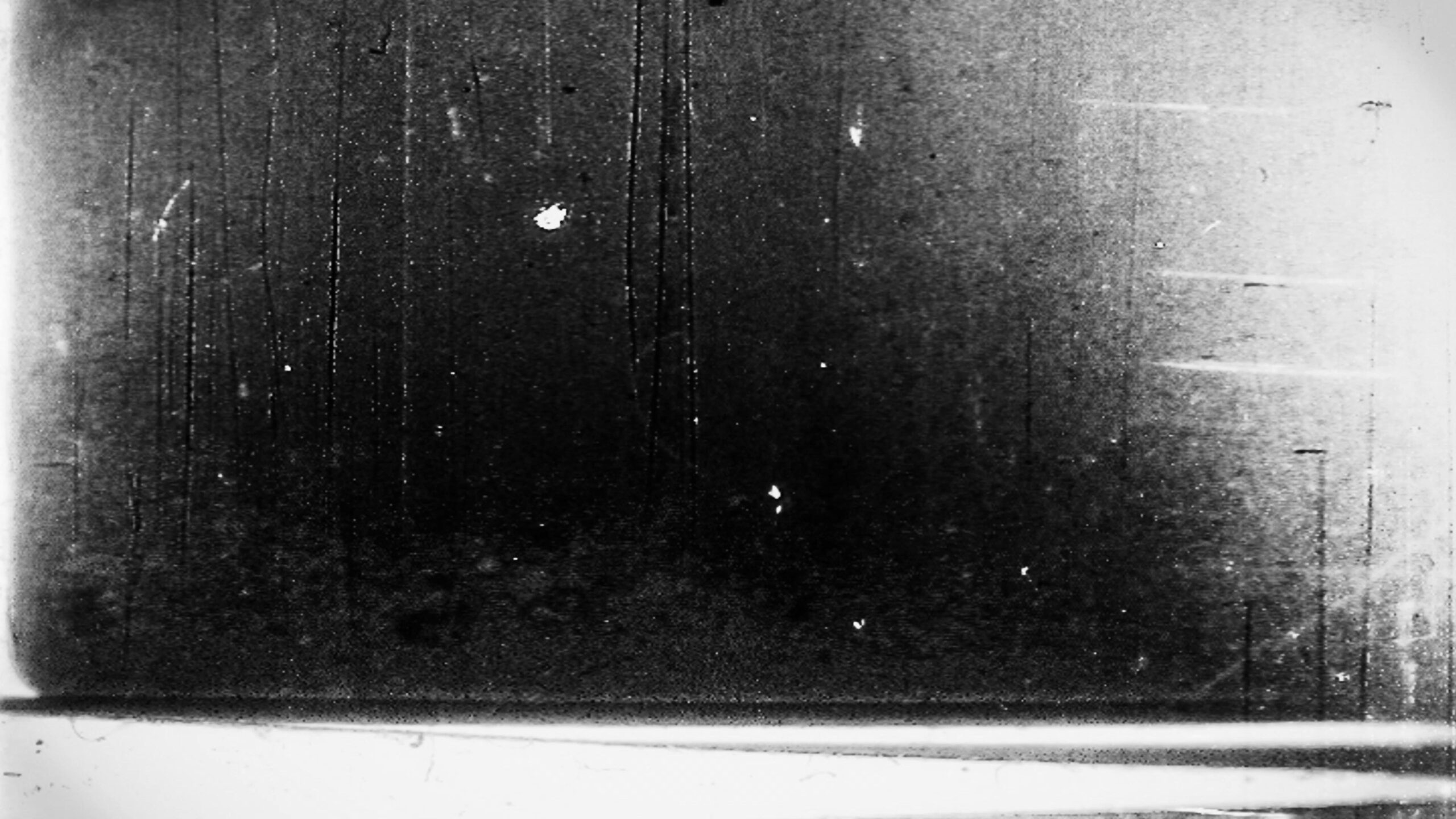 4K video loop of grainy black-and-white 16mm film leader with scratches and static noise.