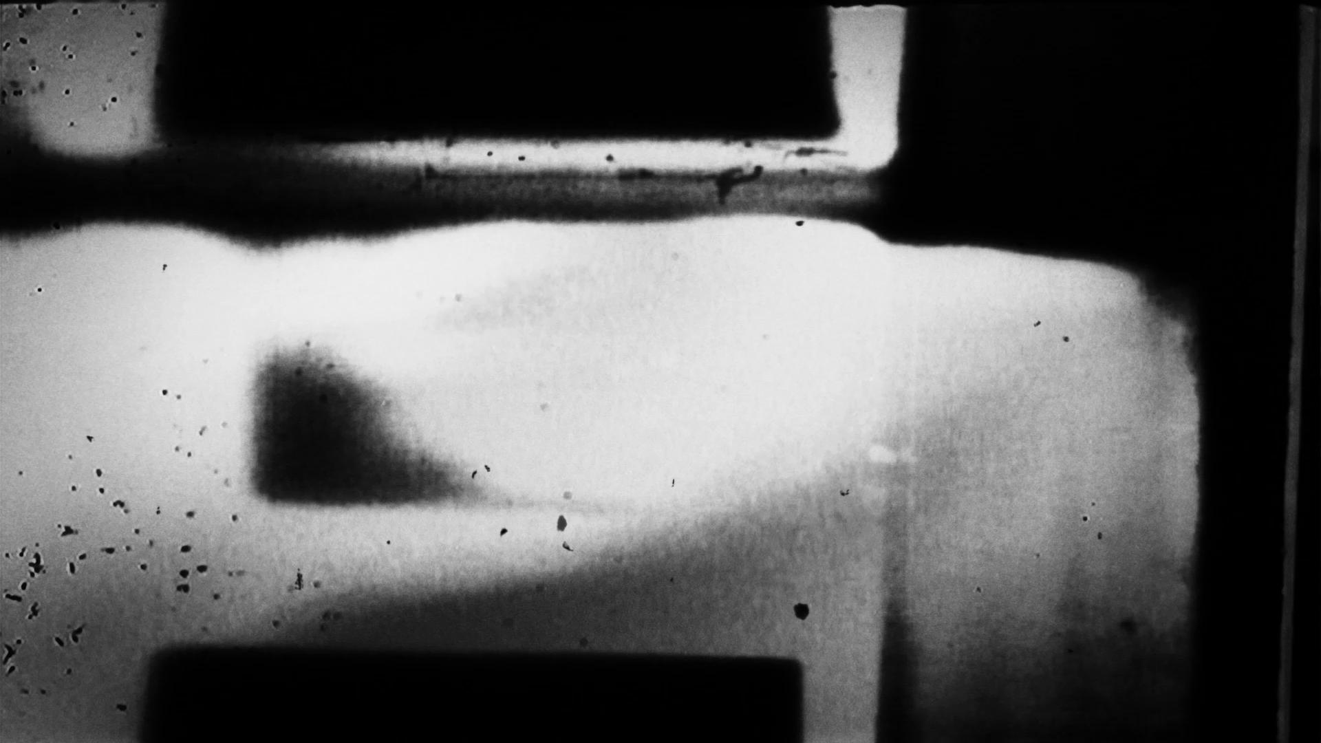 HD video loop of black-and-white 16mm film leader with shadows and texture artifacts.