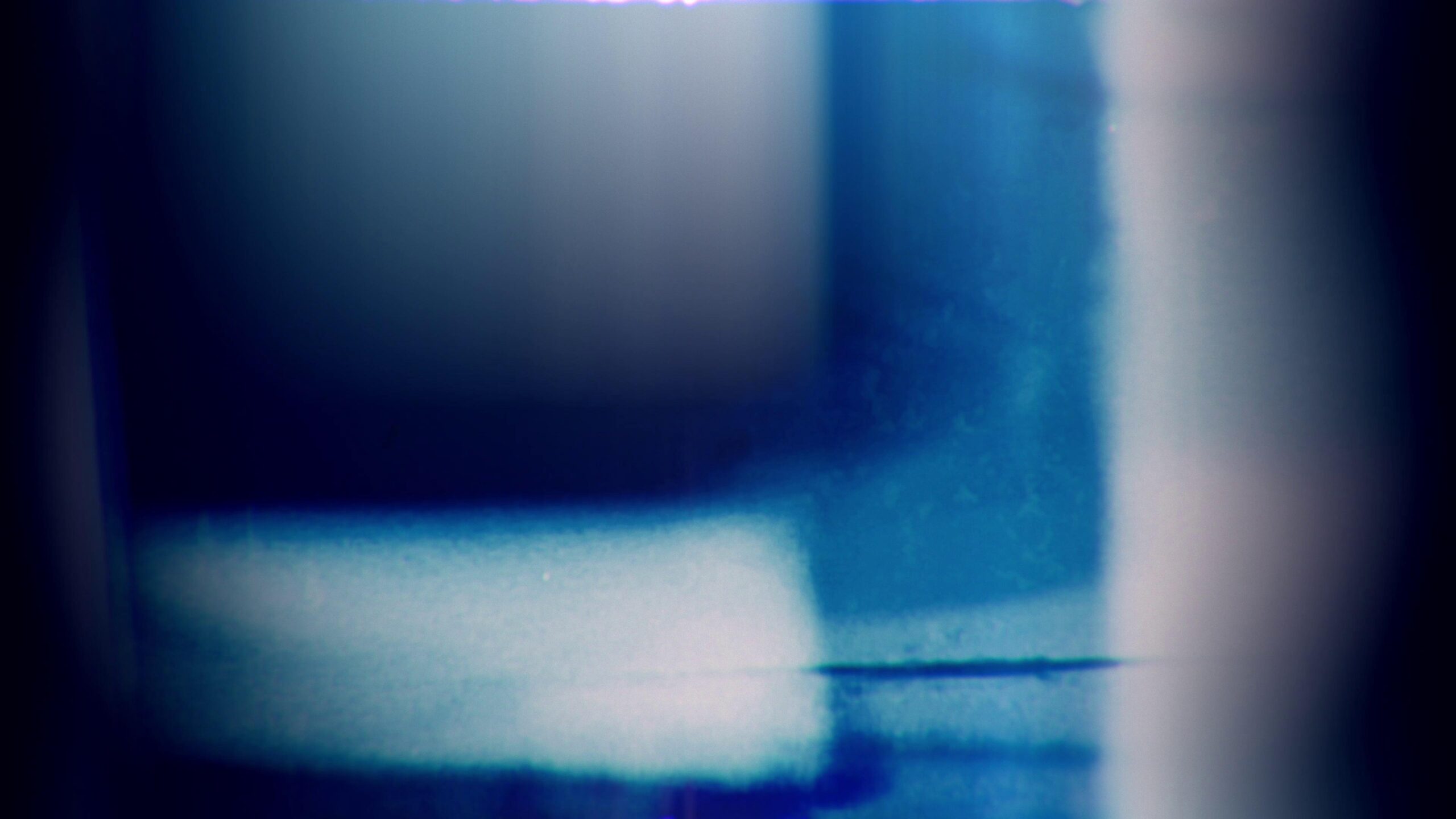 4K video loop of abstract 16mm film leader with blue glow and motion blur effects.