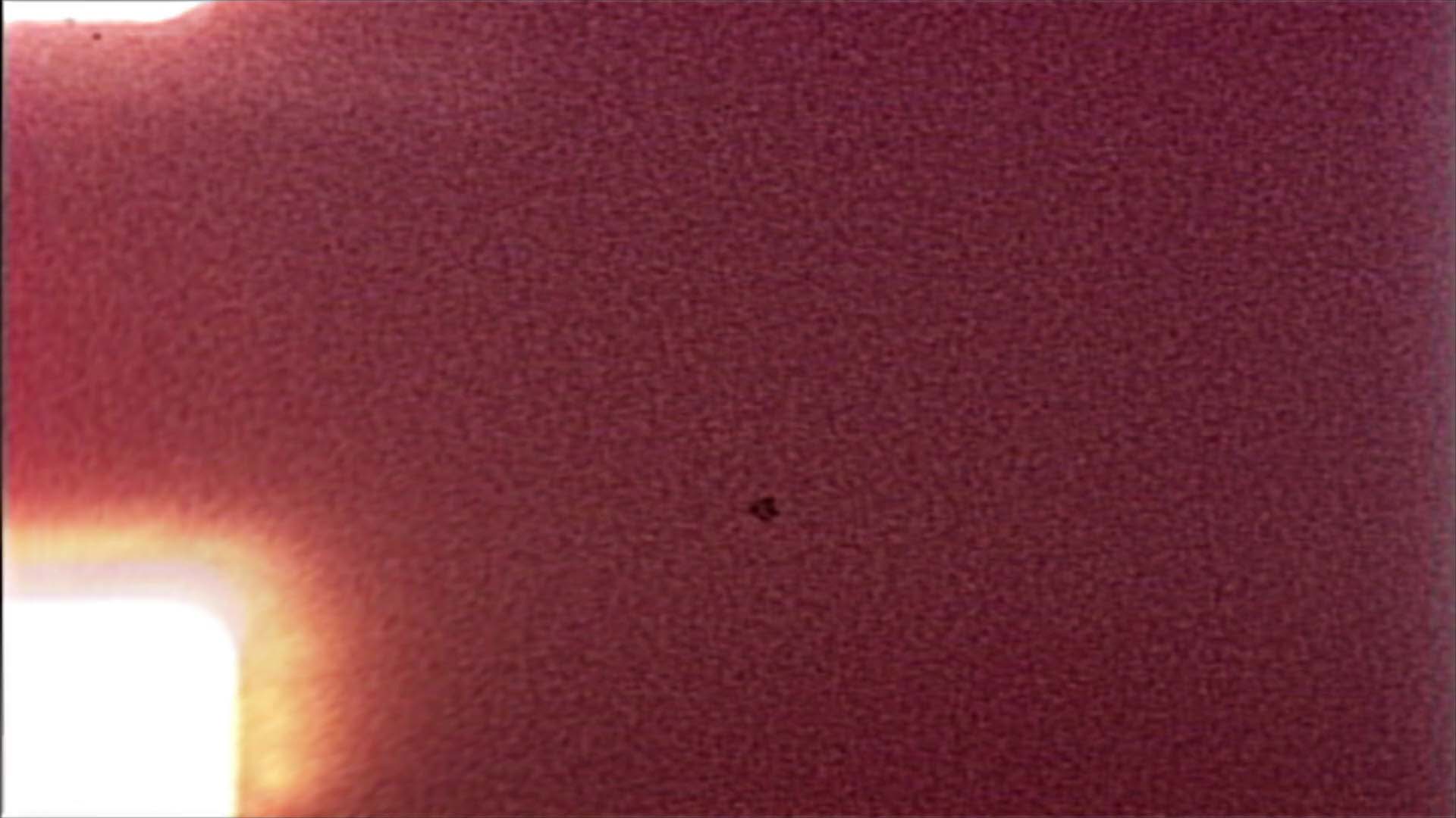 A video loop showing vivid moments from a deteriorating film leader as it flickers violently in a projector.