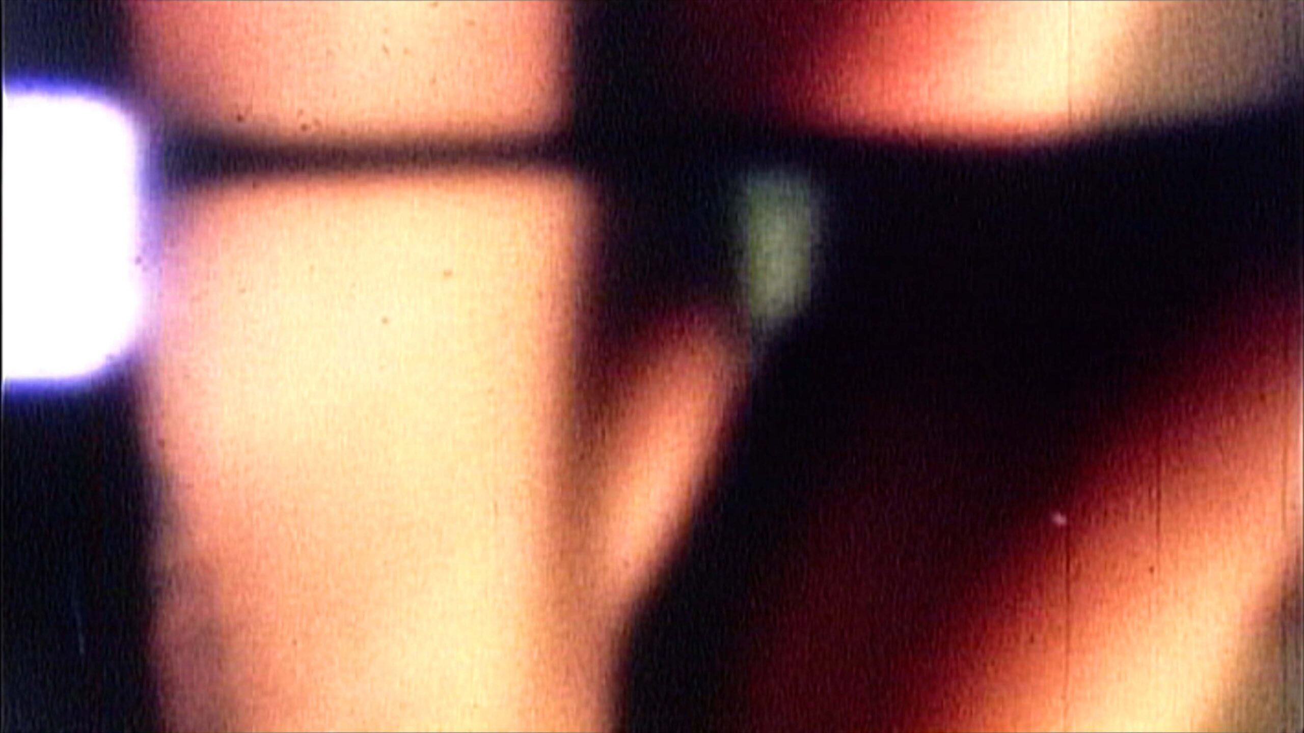 This 4K video loop shows a 16mm film being projected with abstract warm tones, film grain, and projector flare, evoking analog nostalgia and vintage cinematic textures.