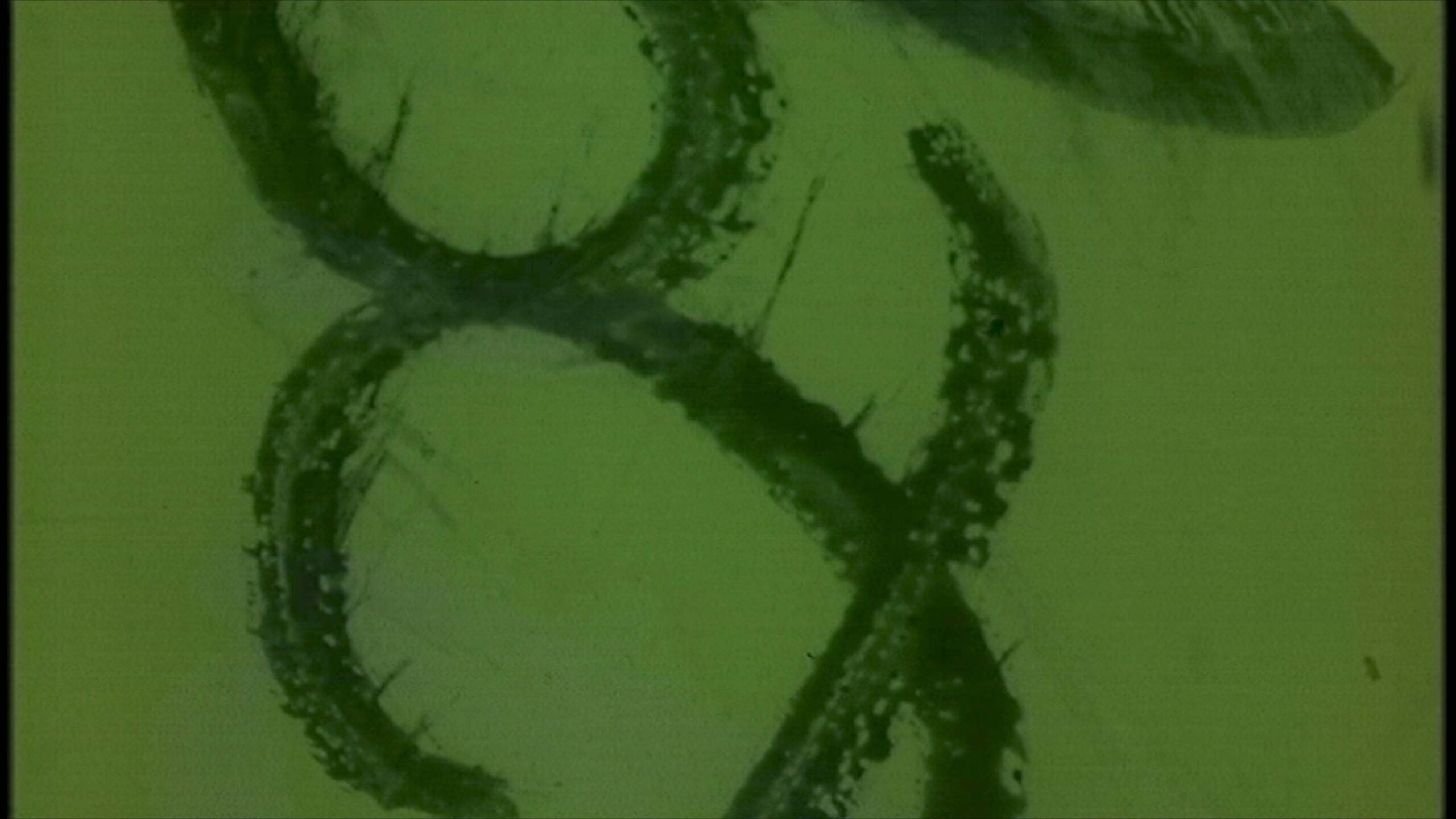 Old-fashioned green-tinted 16mm film leader showing static interference and dot anomalies indicative of analog-era cinematography techniques.
