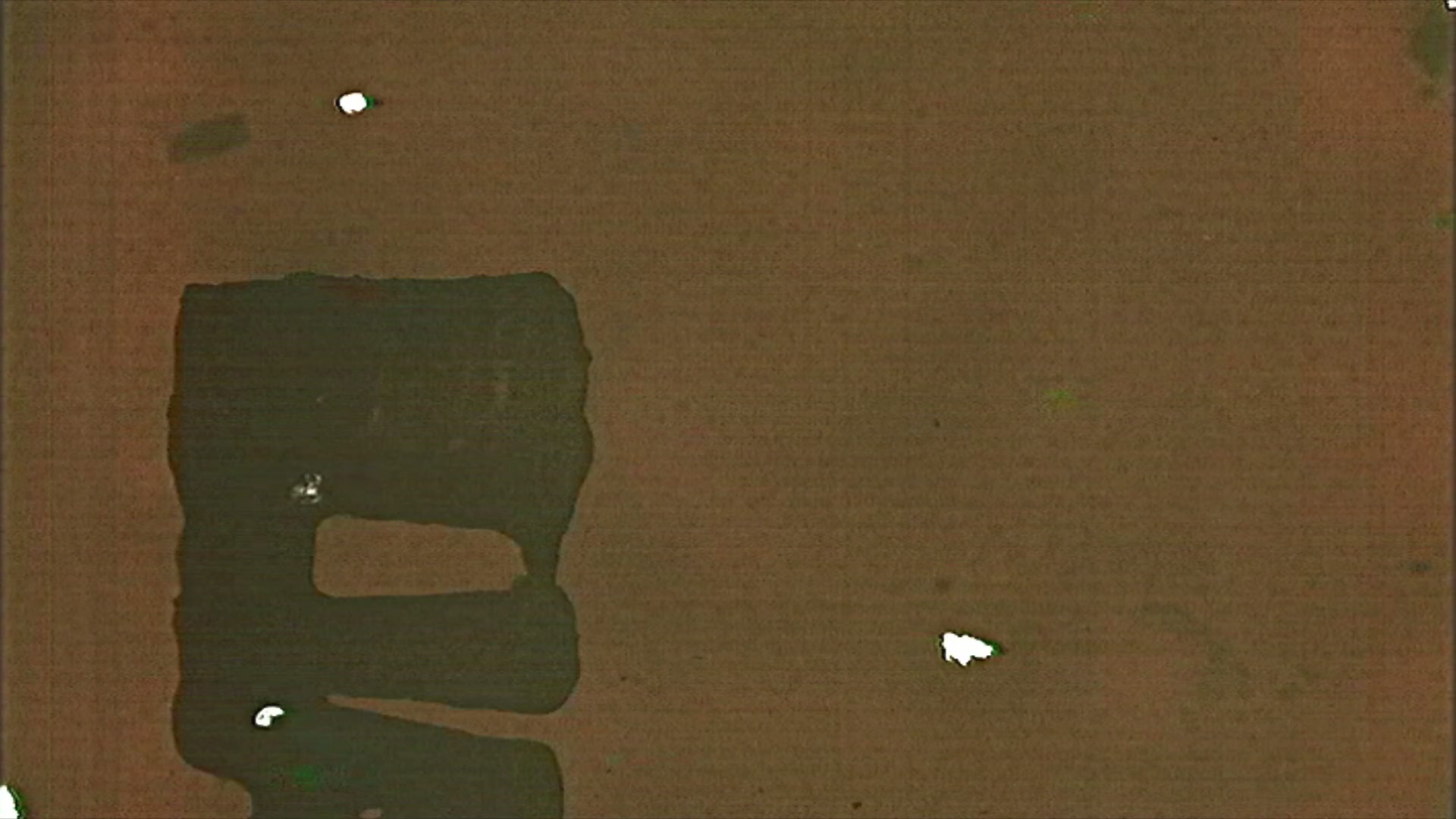 A distressed HD video loop of 16mm film leader with scratches, grain, and aged emulsion texture in warm yellow and green tones.