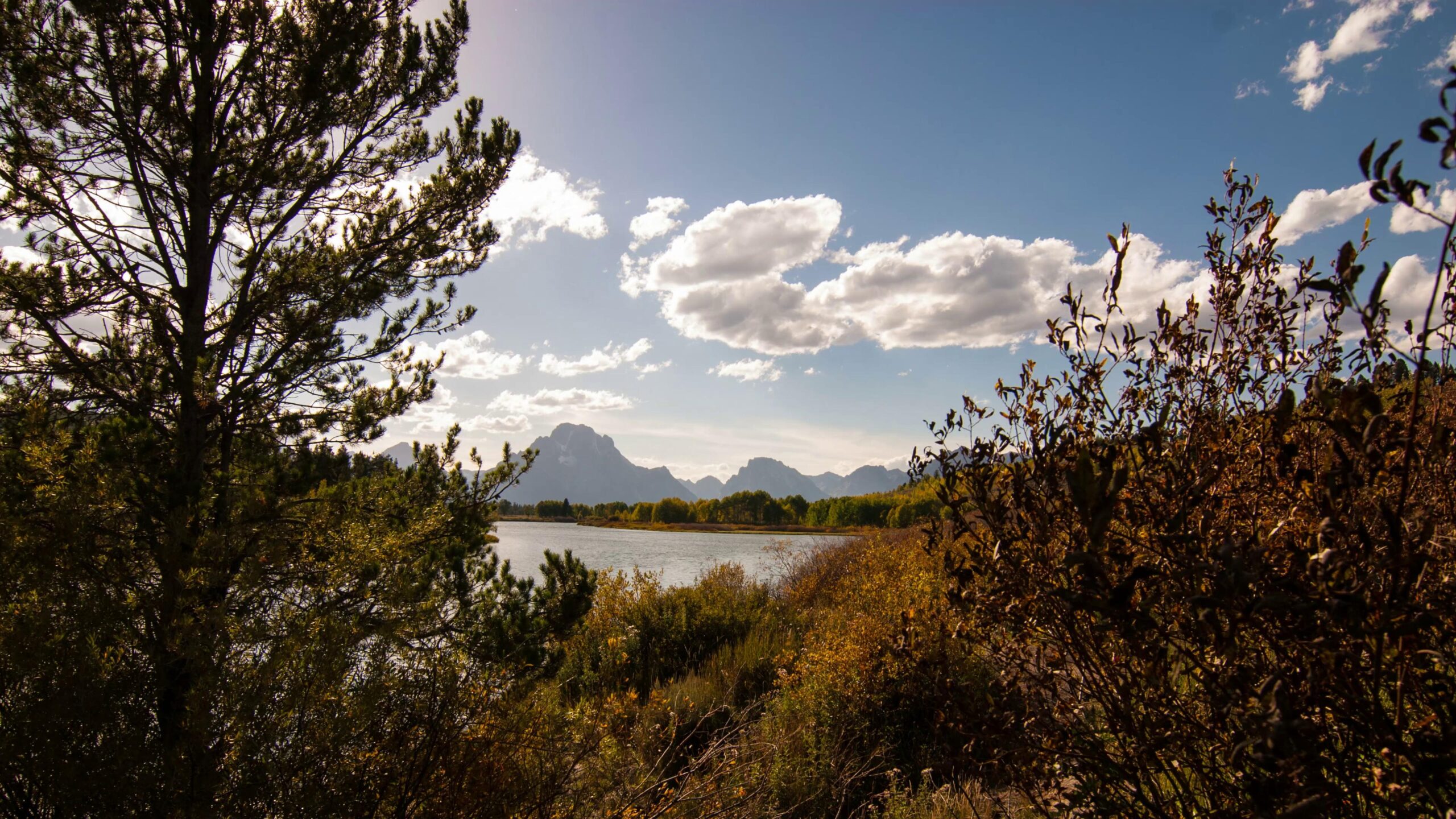 Serene 4K time-lapse landscape with mountains, lake, and autumn foliage.