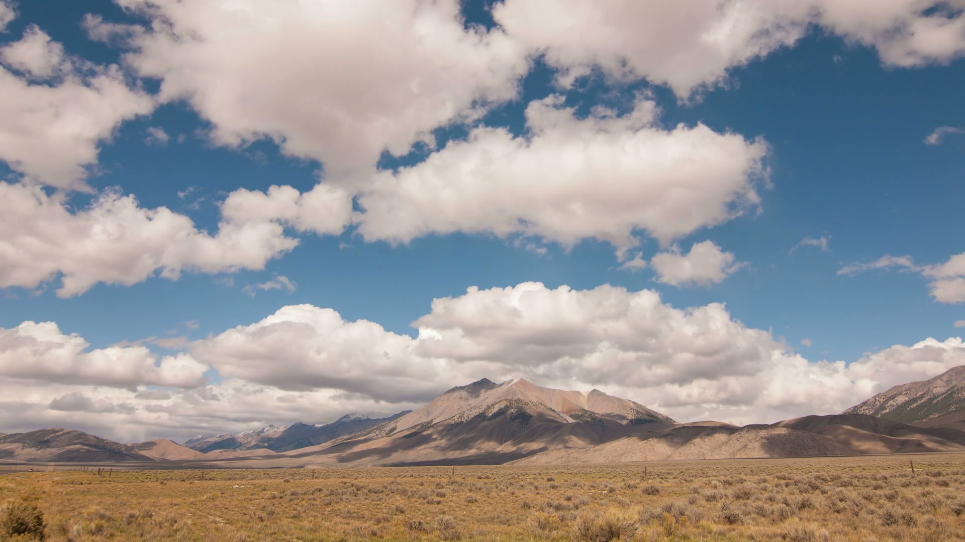 The video captures a breathtaking time-lapse landscape of a vast valley with majestic mountains in the background.