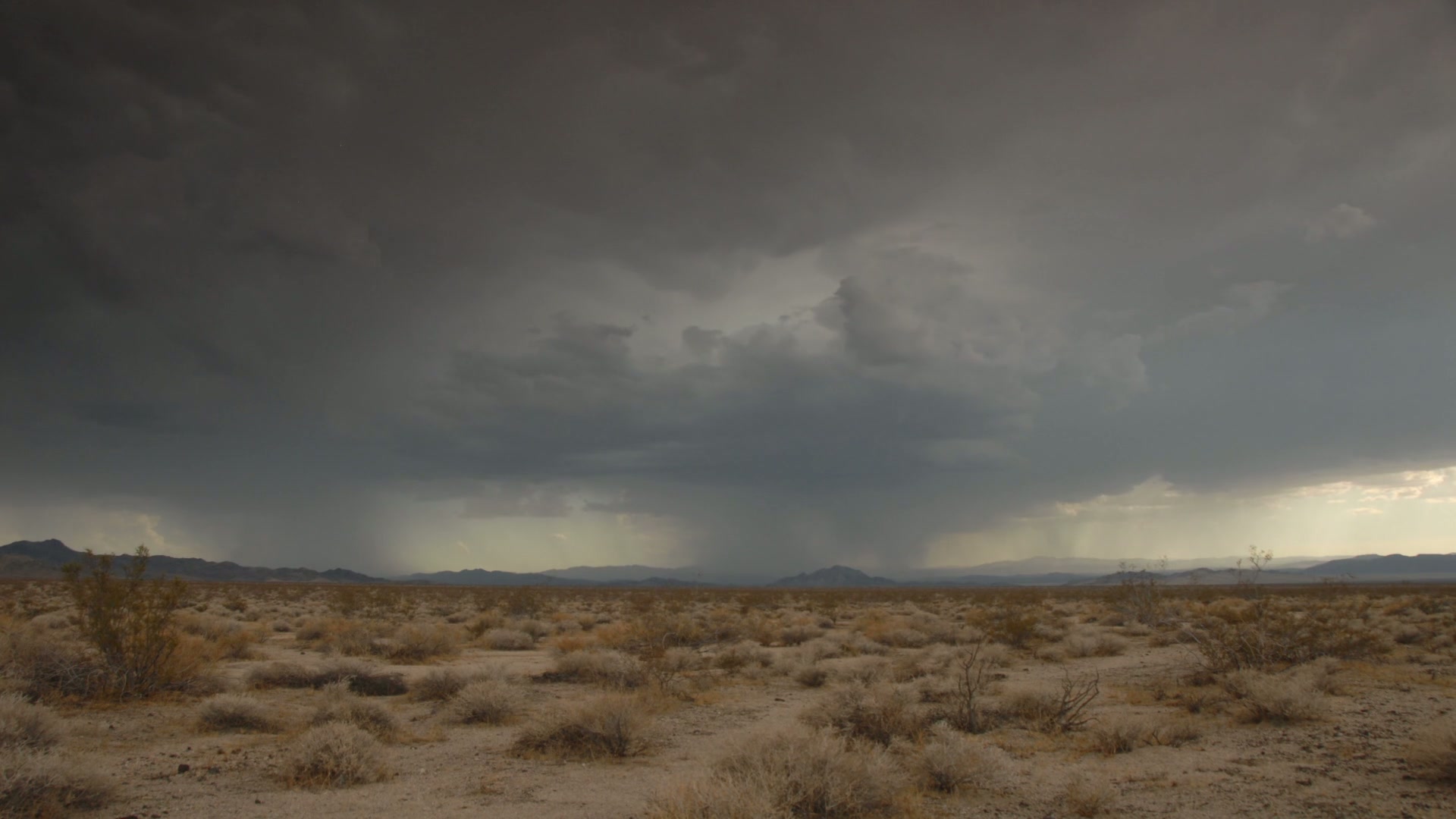 The video captures a vast desert landscape under the looming presence of dark storm clouds and lightning.