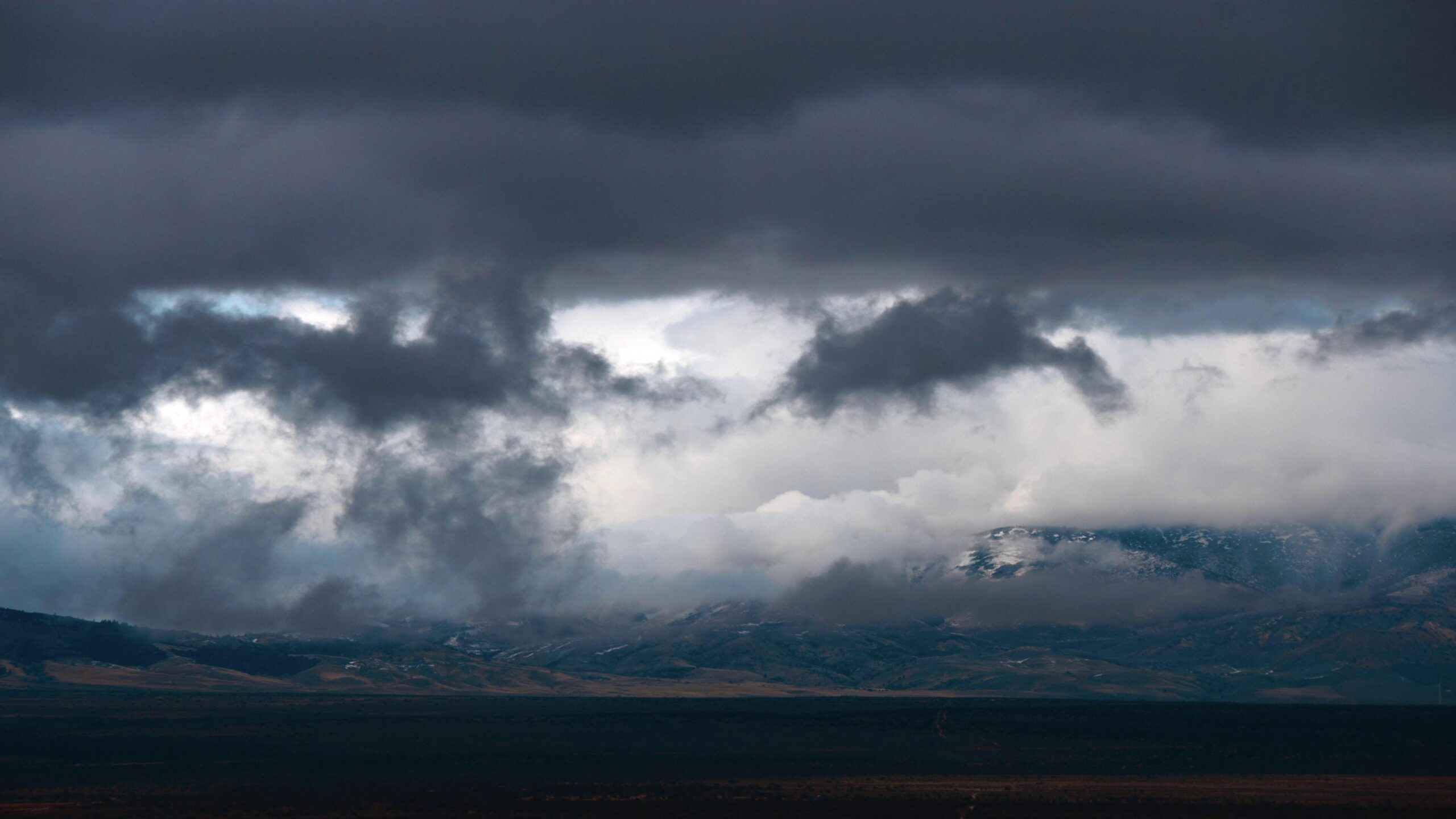 4K video of dramatic time-lapse storm clouds above a snowy mountain range.