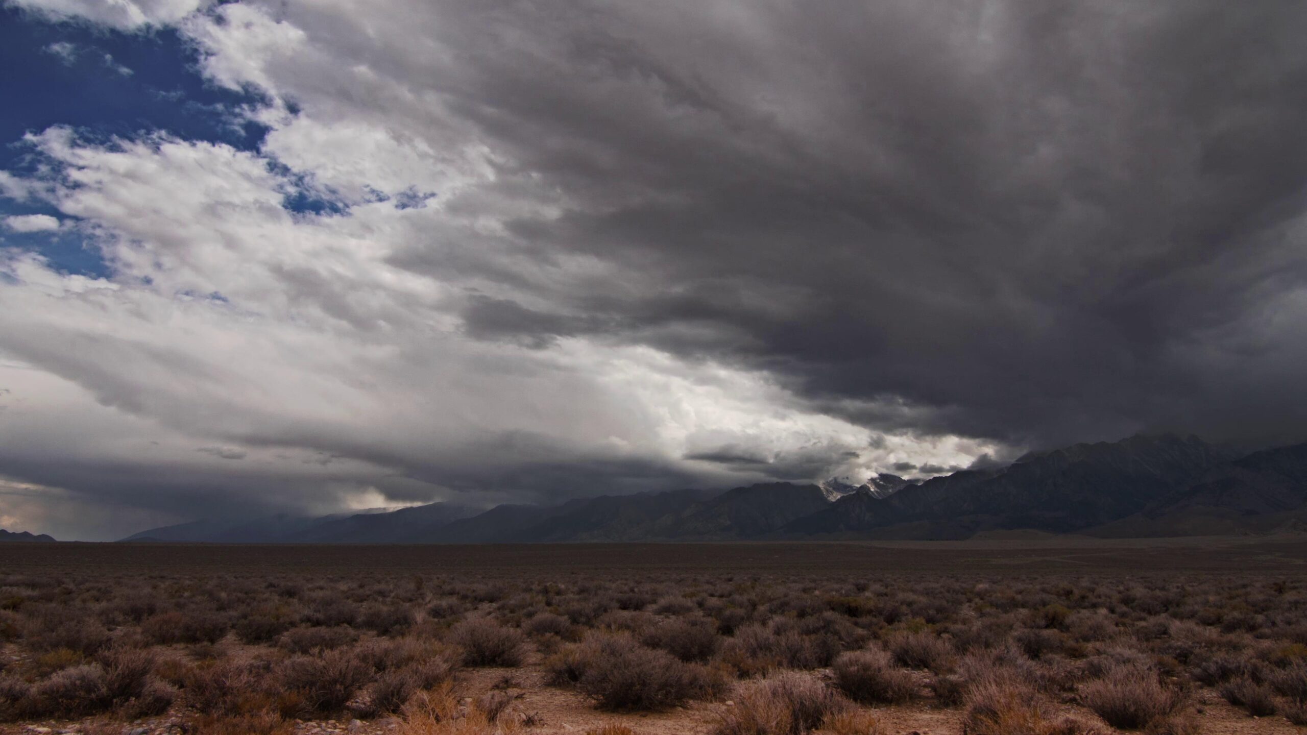 Dramatic desert landscape with time-lapse storm clouds over mountains.