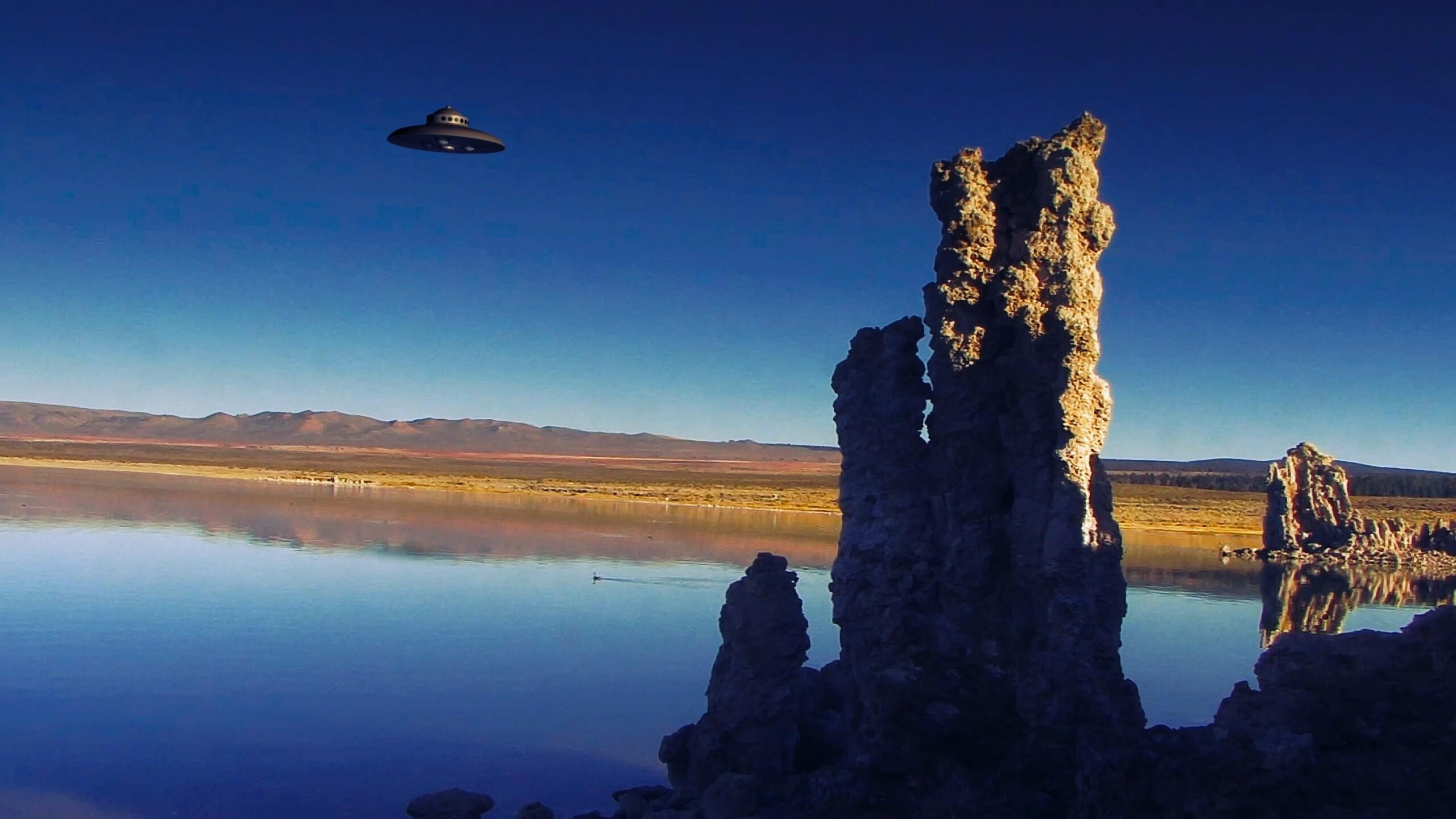 UFO hovering over reflective lake with tufa spires reflecting in calm waters under twilight sky.