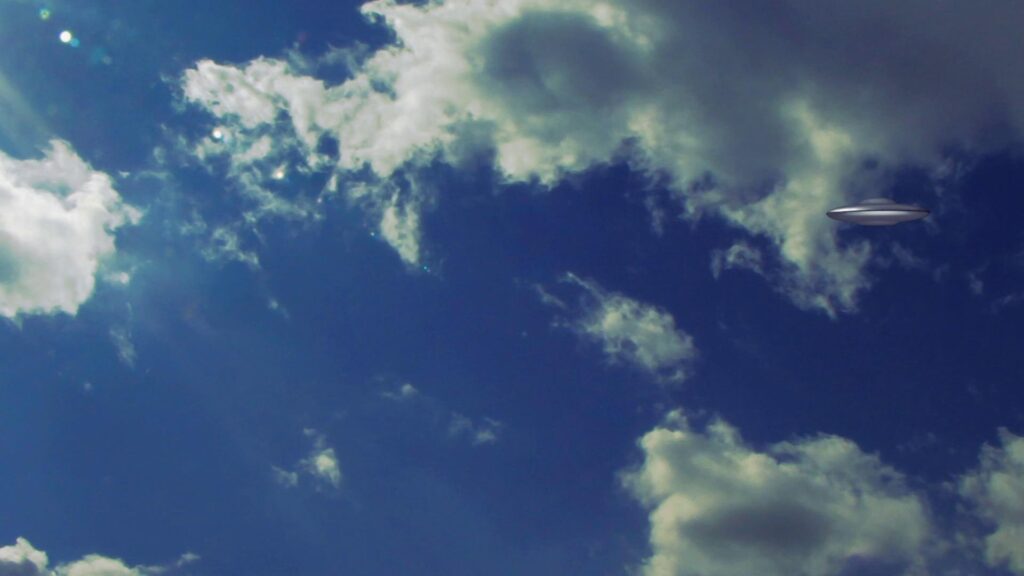 HD video of a UFO traveling in a bright blue sky with fluffy white clouds.