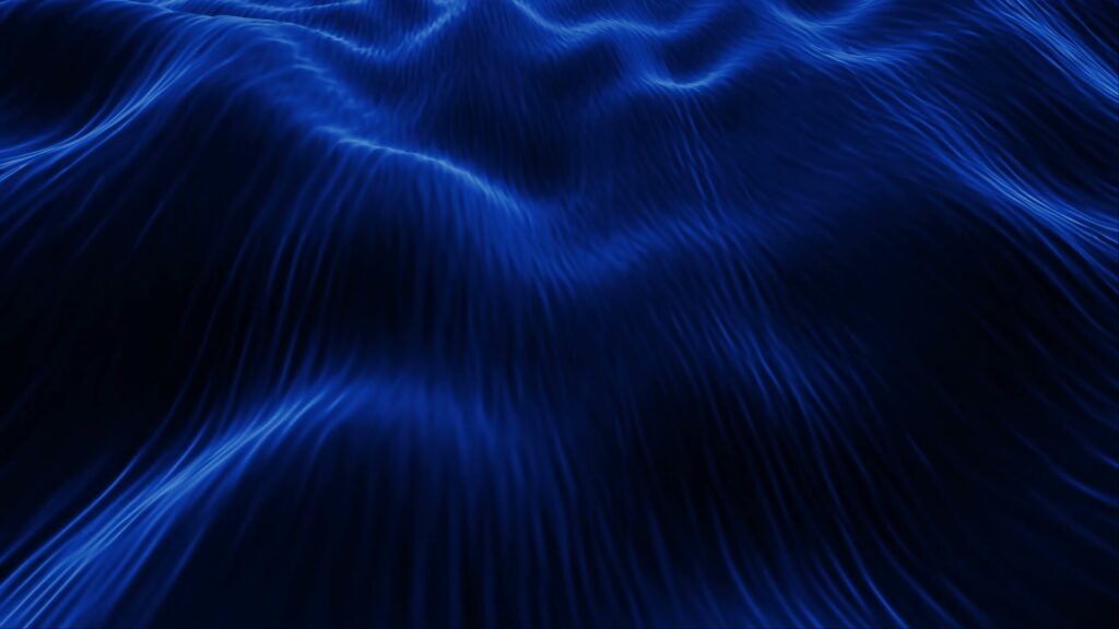 Abstract video loop featuring deep blue undulating waves with a silky texture, illuminated to highlight the flowing contours, evoking a sense of tranquility and dynamic motion.