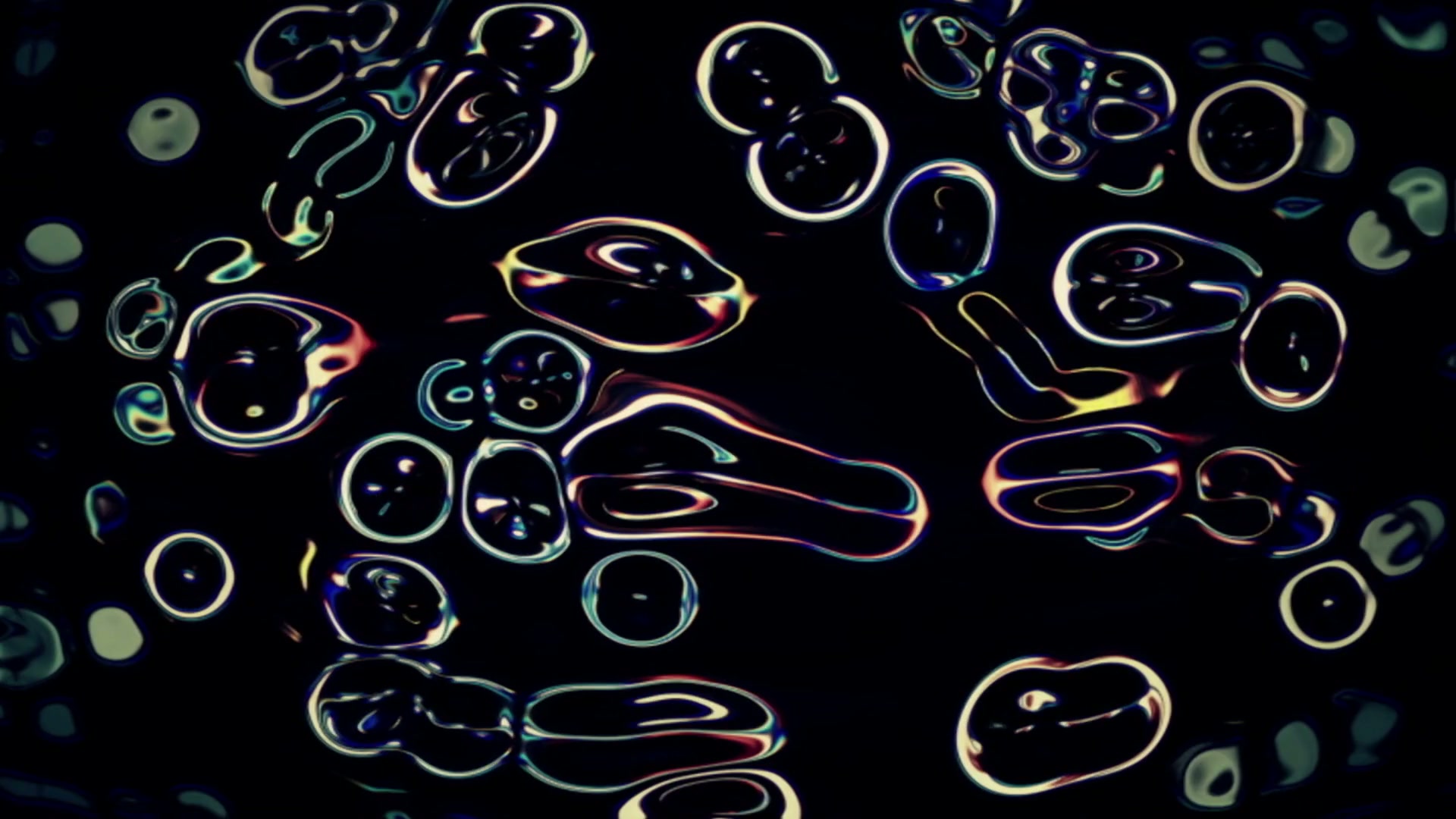 Abstract video loop featuring glowing, iridescent shapes resembling cellular structures against a dark background, with vivid colors creating a dynamic, luminescent effect.