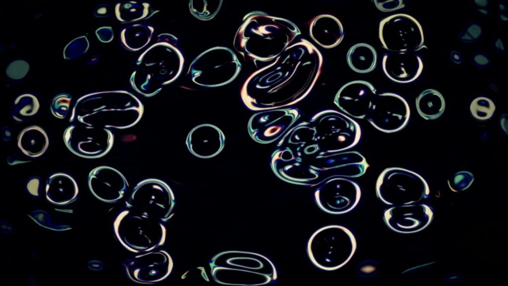 A vibrant abstract looping video featuring luminous, colorful bubble-like shapes with swirling patterns against a dark background.