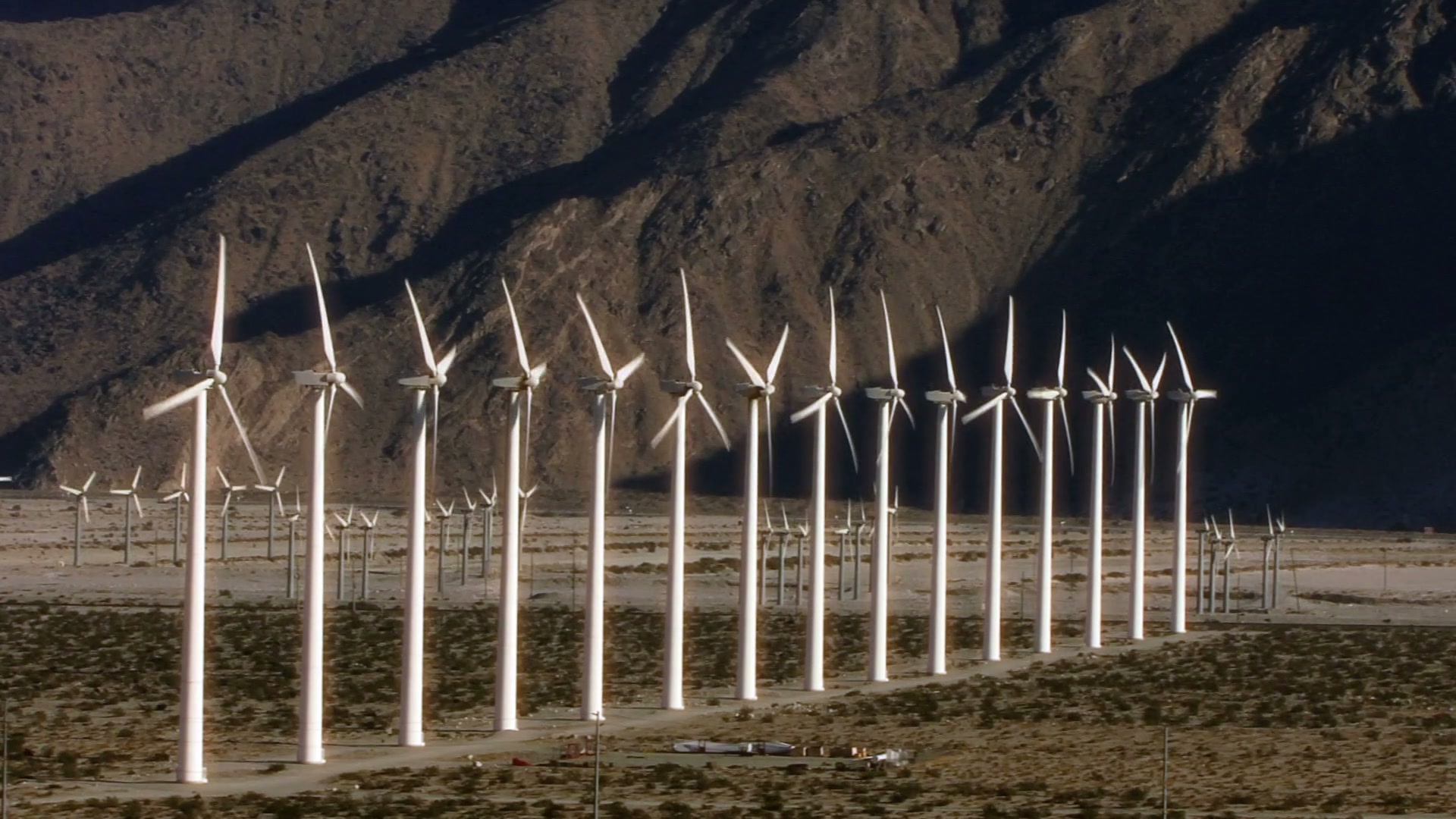 The video depicts a large wind farm set against the backdrop of a rugged, mountainous landscape.